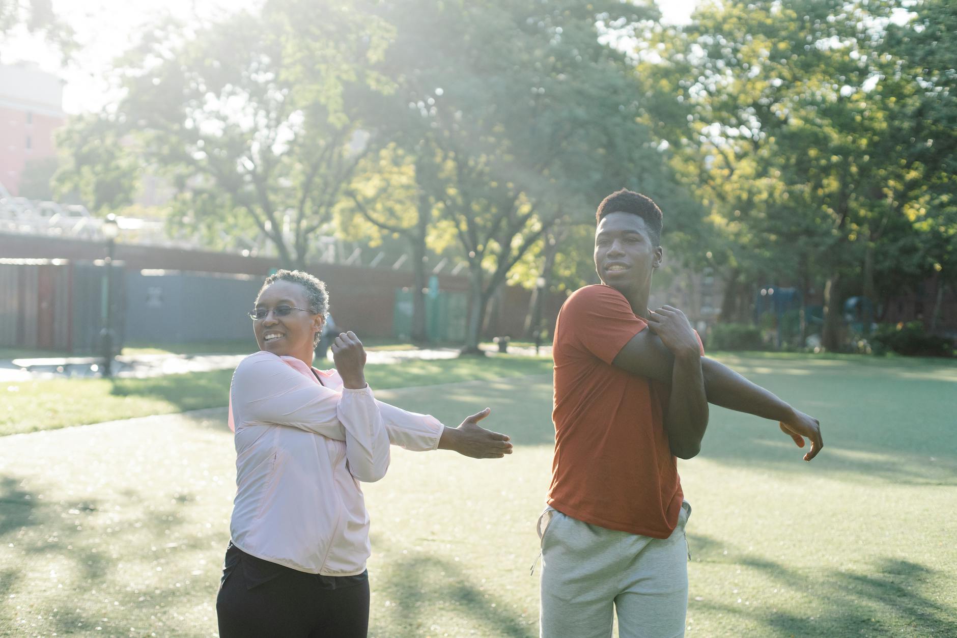 Two diverse adults stretching in a sunny park, embracing a healthy lifestyle. - daily stretching routine