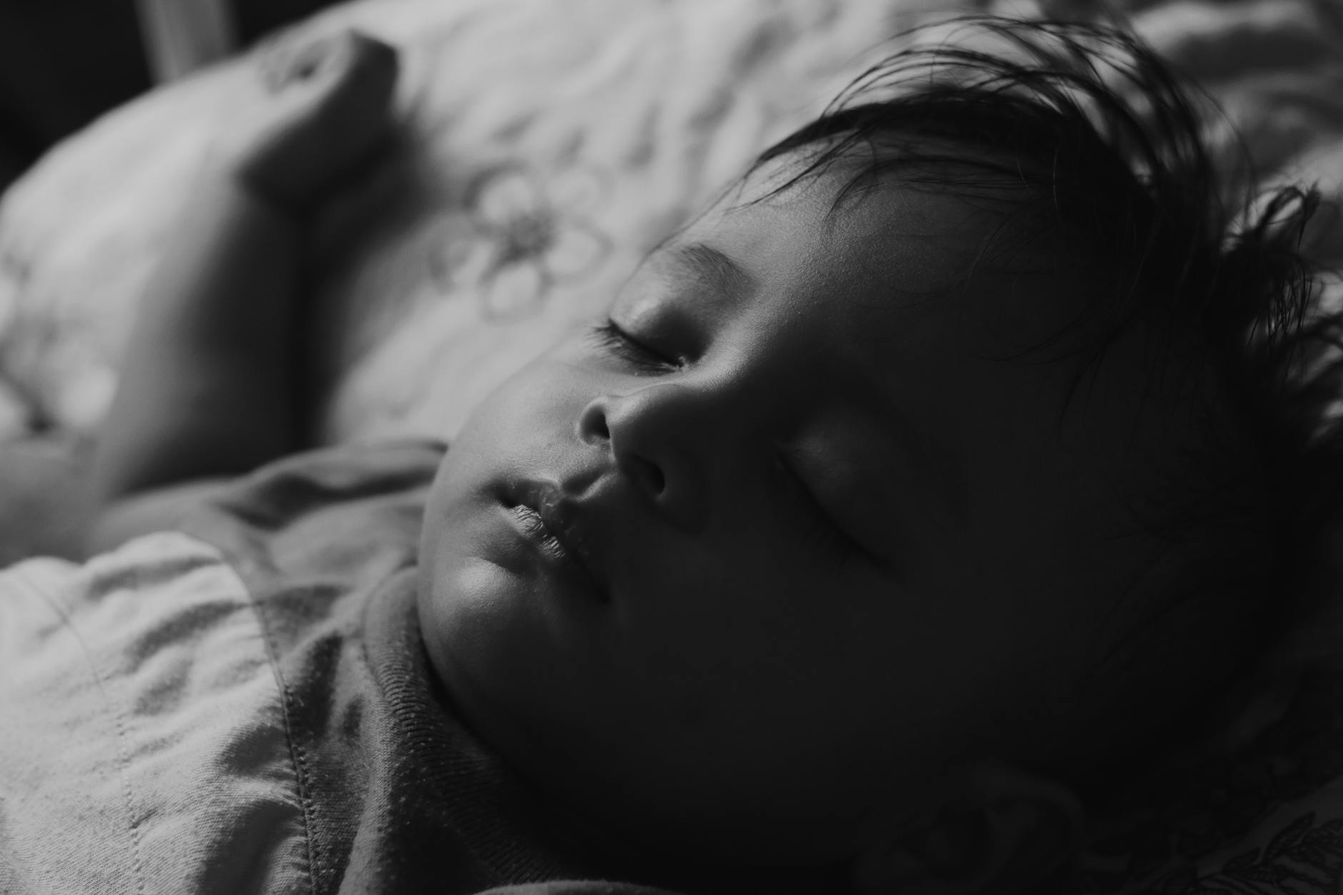 Close-up of a sleeping baby boy indoors, captured in calming black and white tones. - daylight sleep science