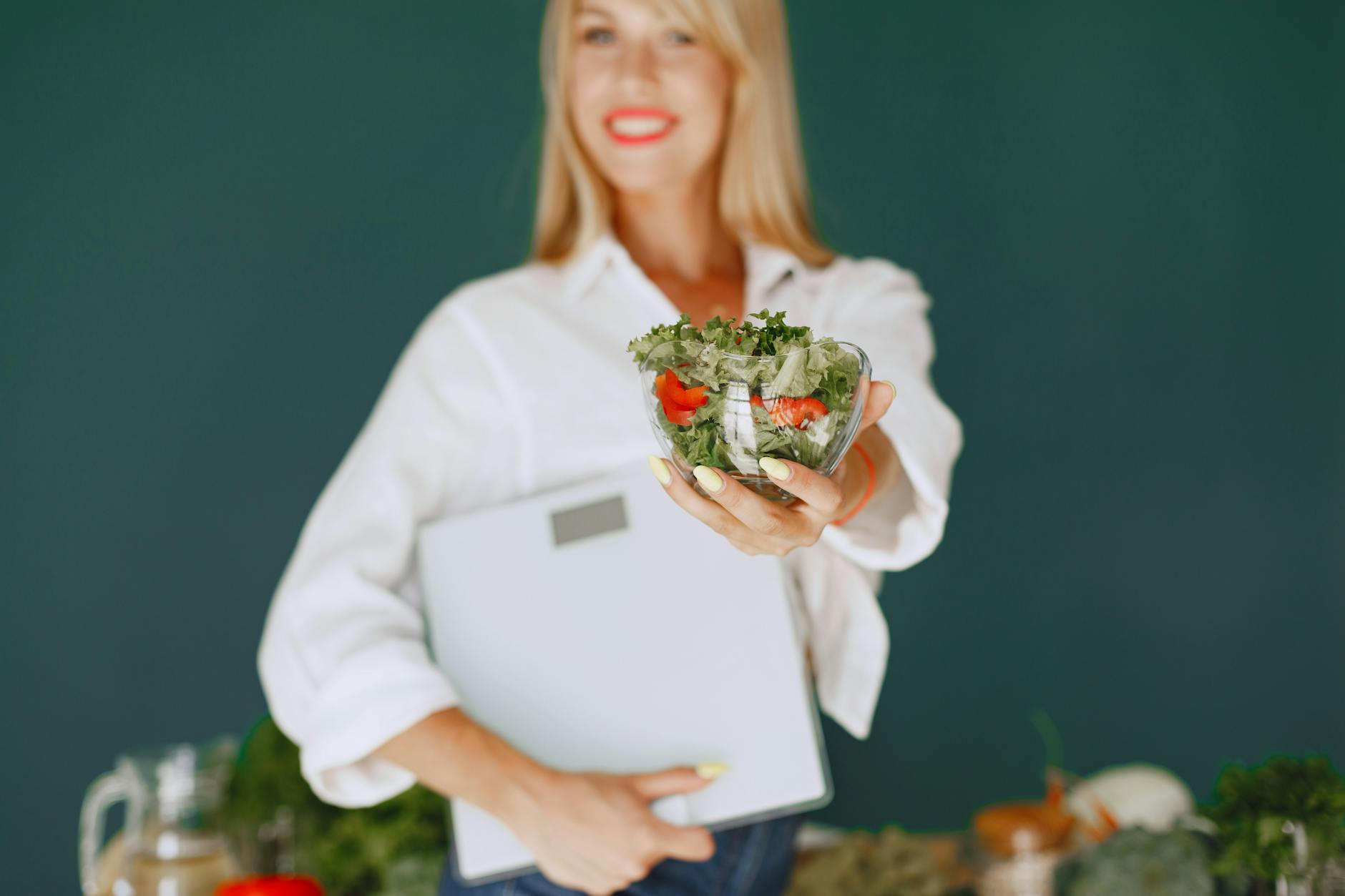 A woman with a vibrant smile offering a fresh salad bowl, promoting healthy eating. - declutter diet habits