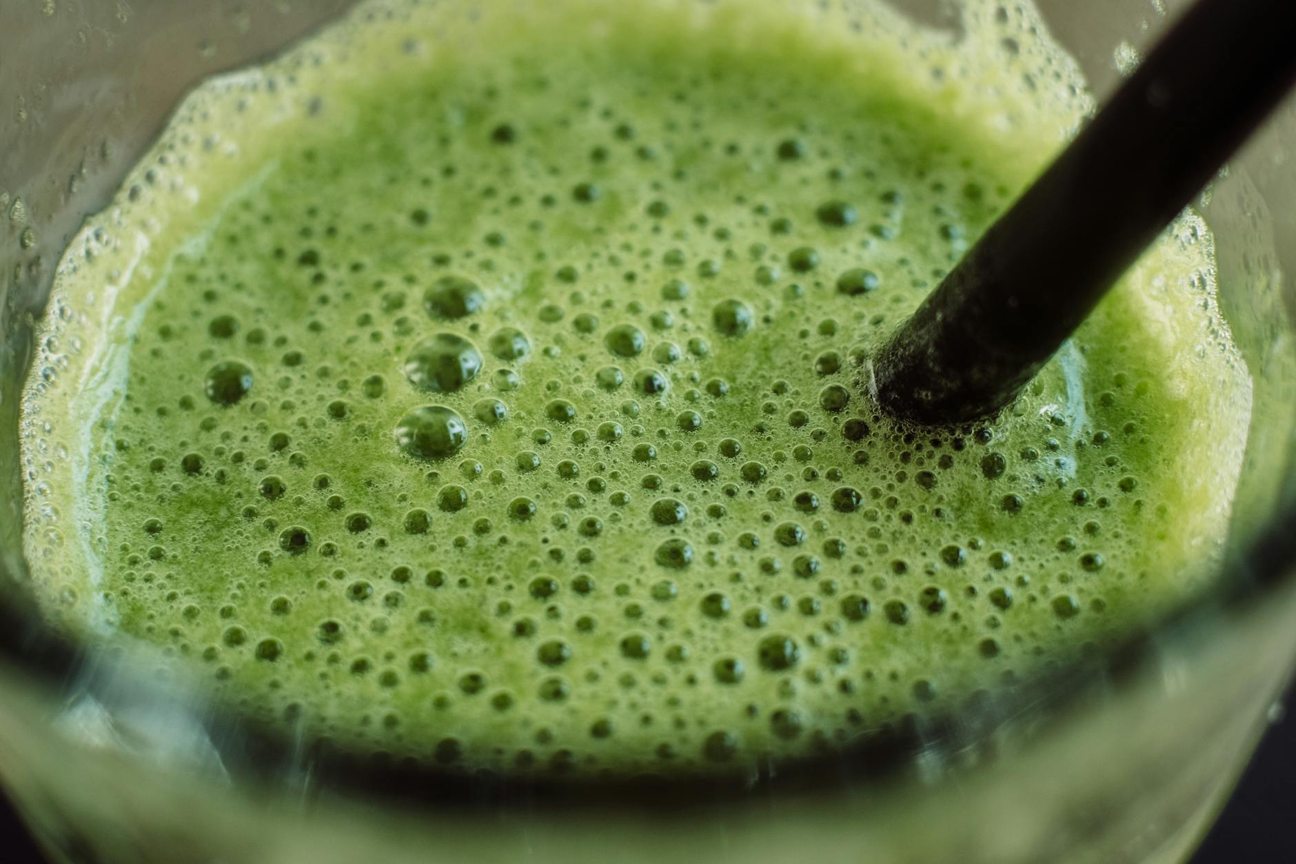 Close-up of a frothy green smoothie with bubbles and a straw for a fresh start. - detox smoothies