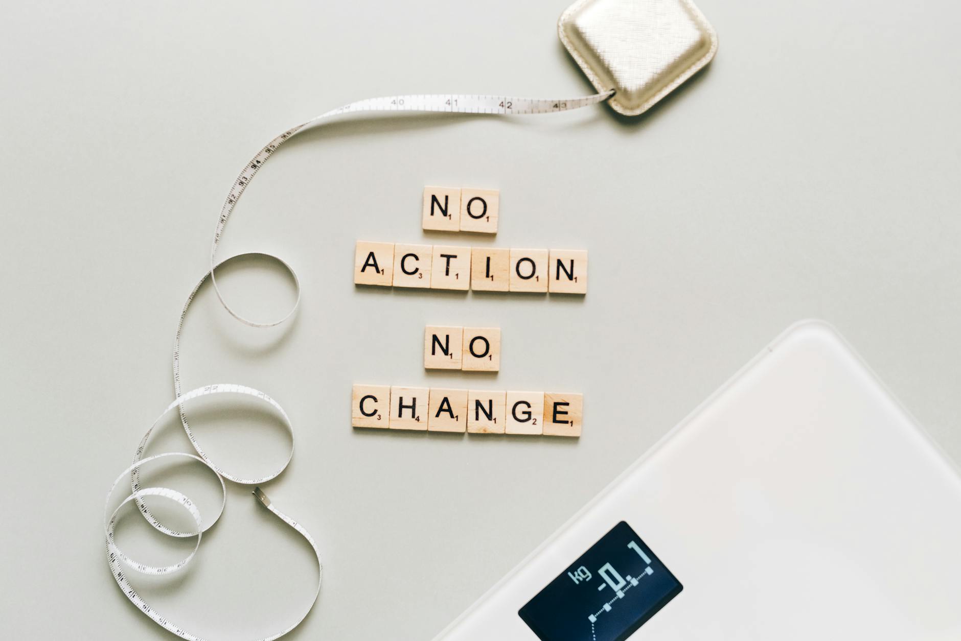 Motivational concept with scrabble tiles spelling no action no change alongside a measuring tape and scale. - easy weight loss