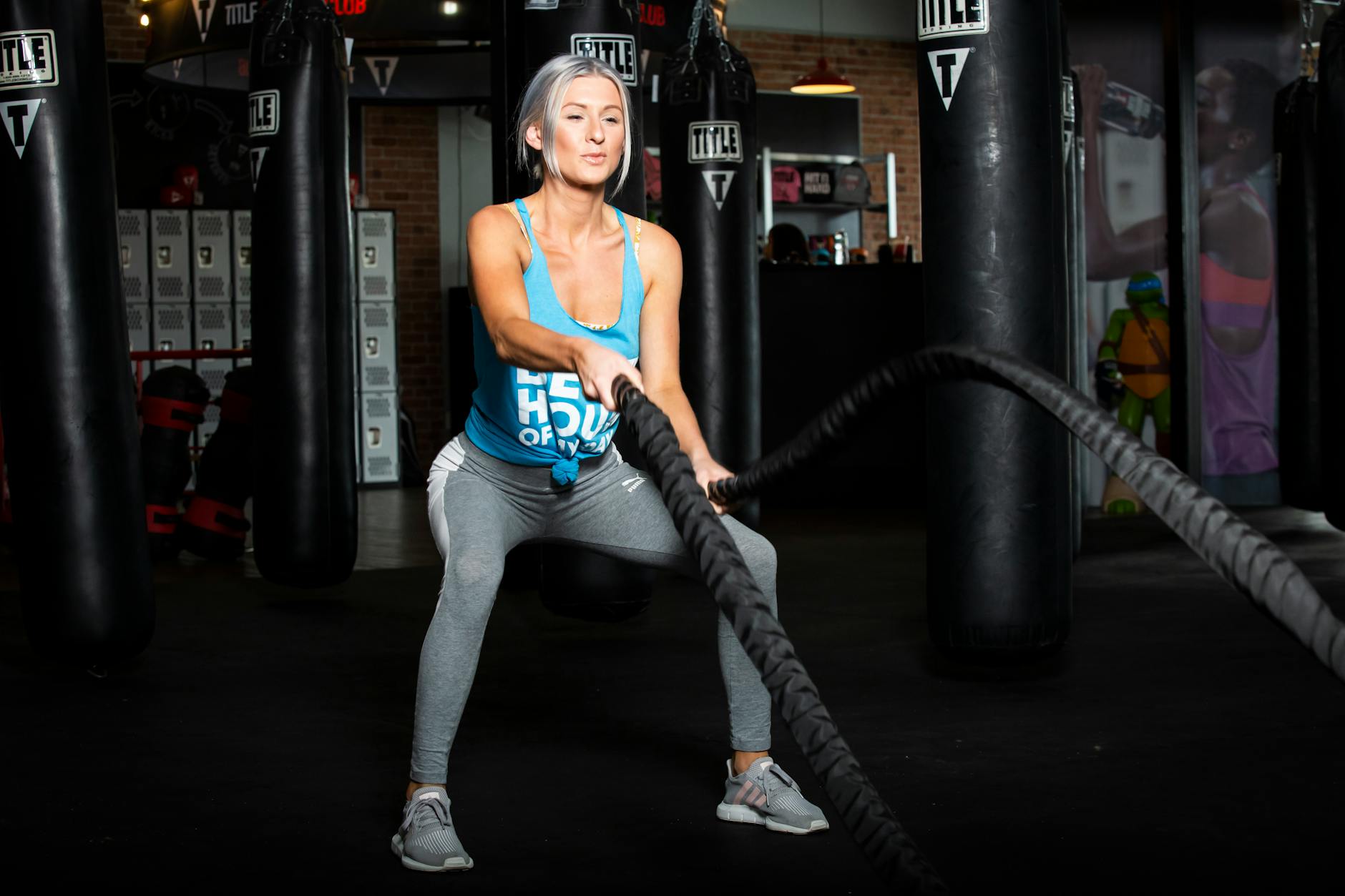 Woman working out with battle ropes in a gym, promoting a healthy lifestyle. - fat burning workouts