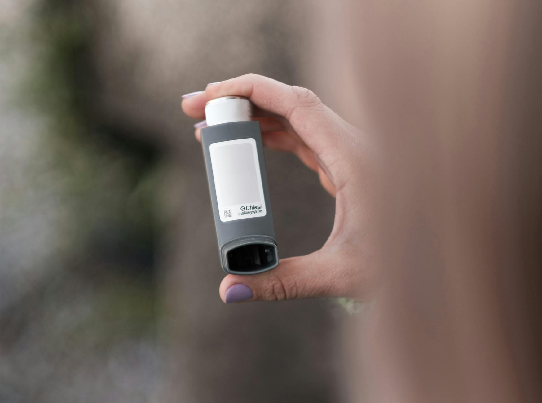 A person holding a gray asthma inhaler outdoors. Health and medical concept. - foods for allergy relief