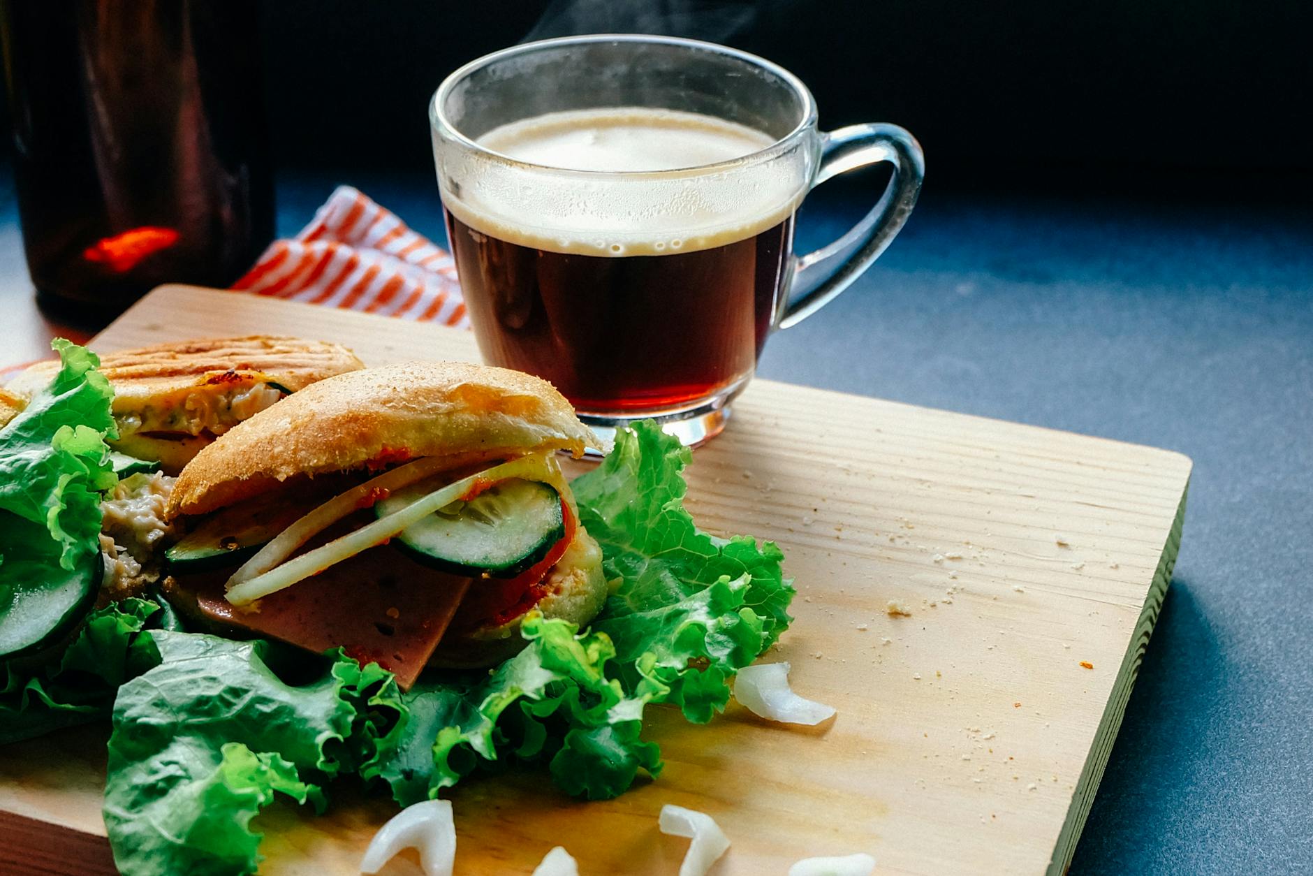 Tasty sandwich with fresh ingredients next to a steaming cup of coffee on a wooden board. - healthy breakfast sandwich