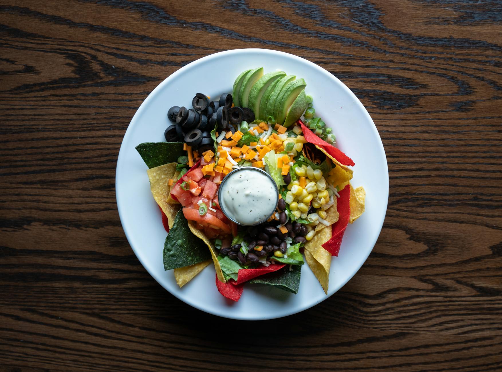 Colorful plate of nachos with fresh avocado, olives, tomatoes, and cheese for a tasty Mexican meal. - healthy chips