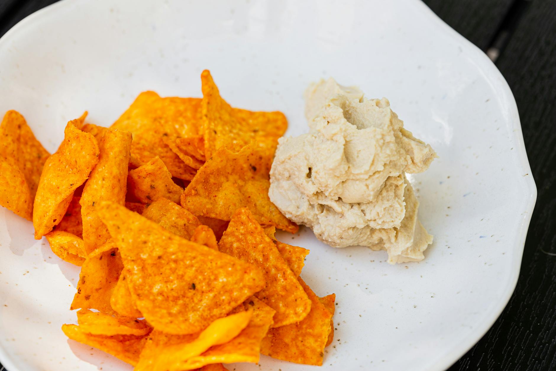 A close-up shot of spicy nachos served with creamy hummus dip, perfect for snacking. - healthy chips