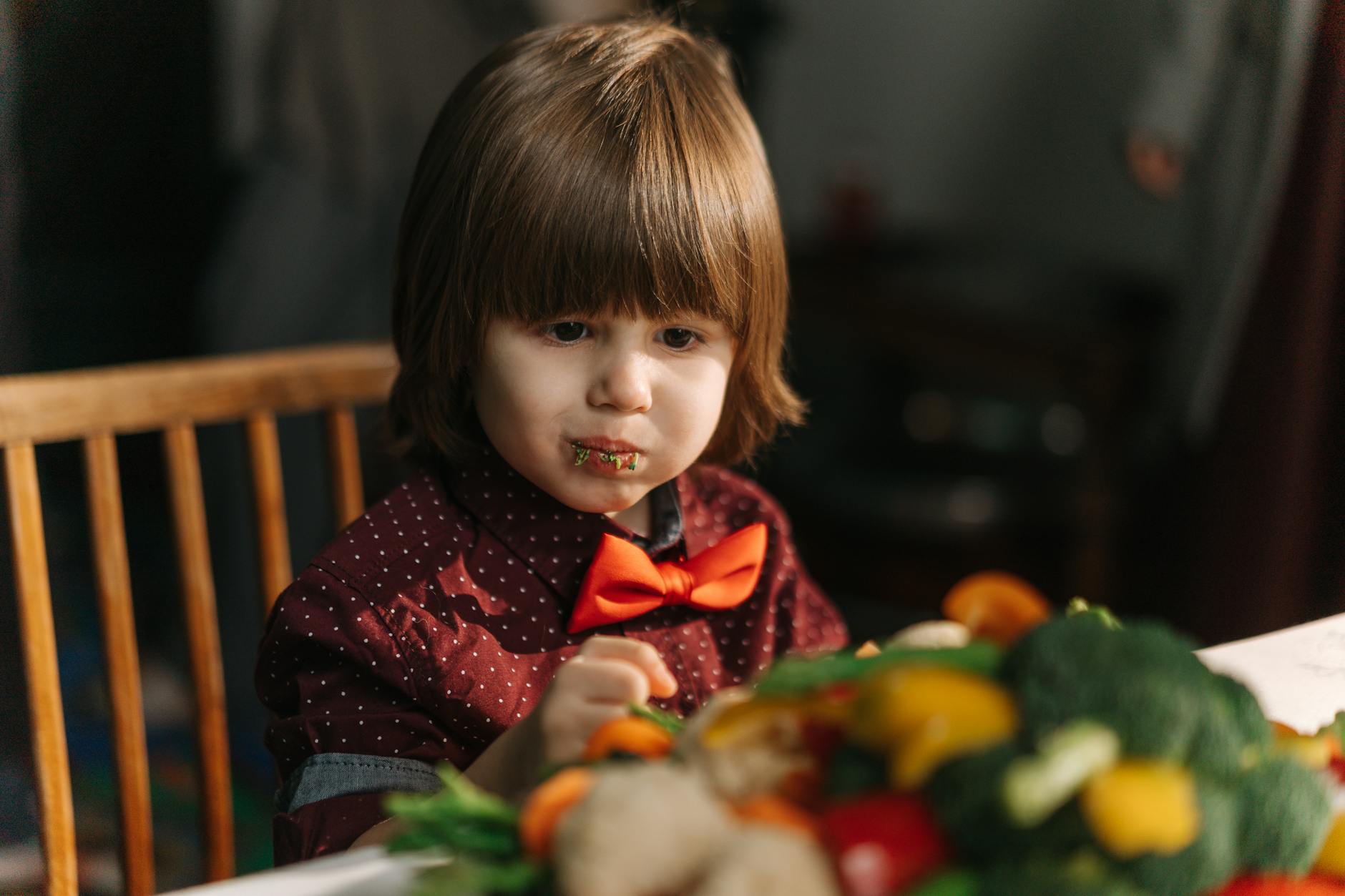 Adorable child enjoying fresh vegetables at the dinner table. - healthy kid meals