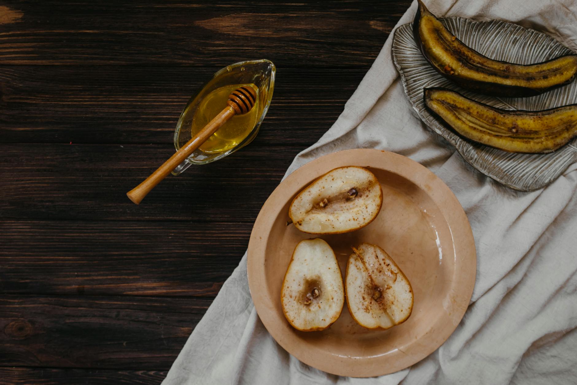 Overhead shot of baked pears and ripe bananas with honey on a wooden table. - healthy lunch recipes