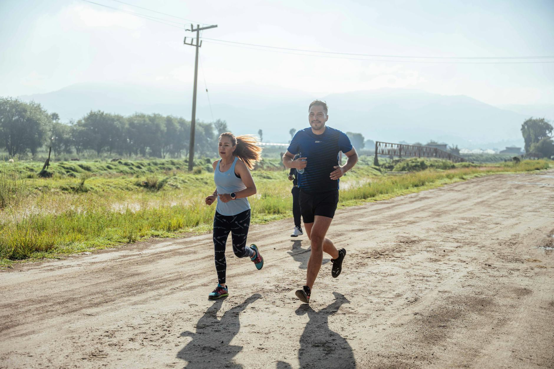 Group of joggers running along a rural dirt path surrounded by nature. - healthy morning habits