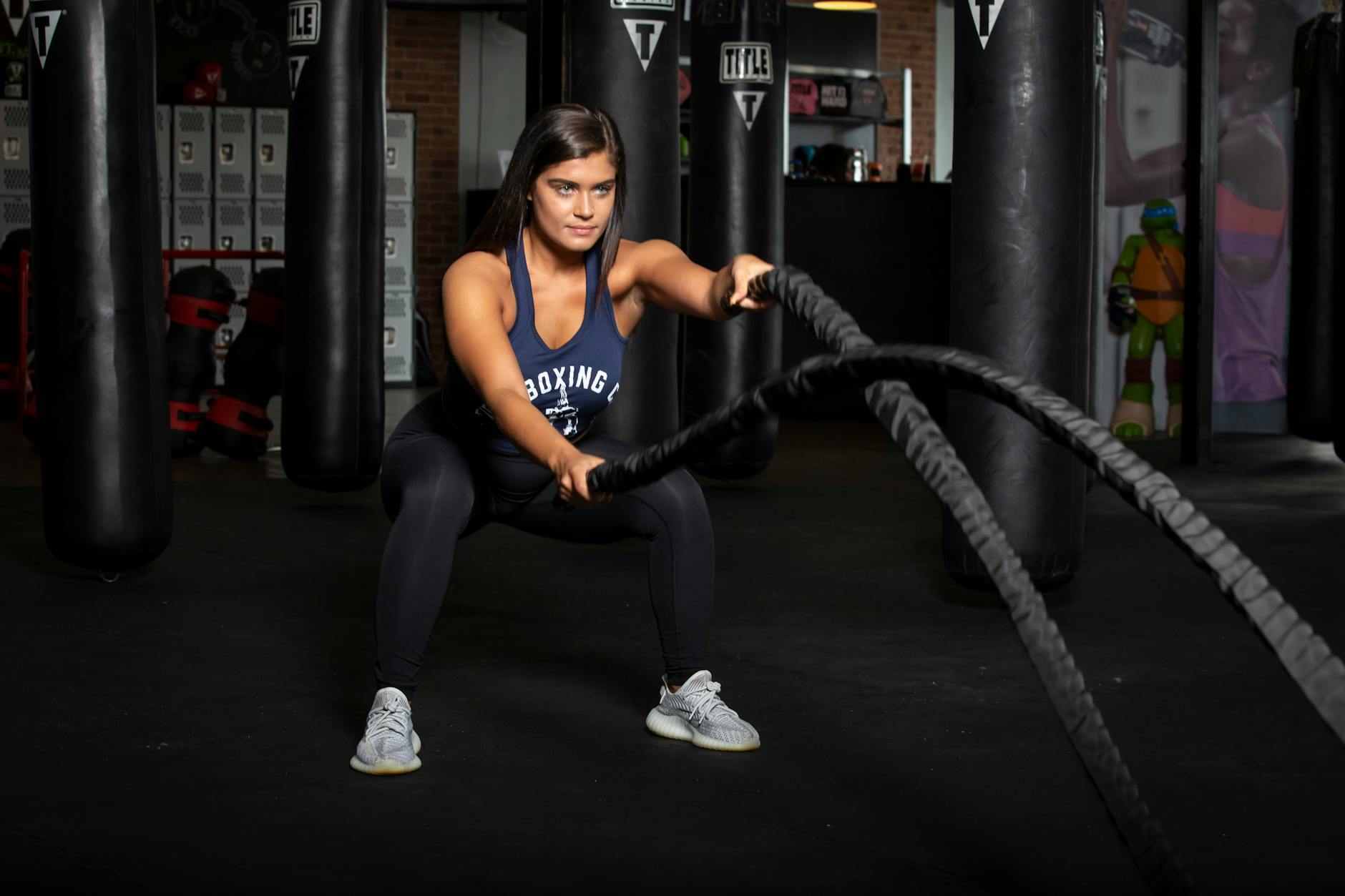 Female athlete working out with battle ropes in a modern gym setting. - high intensity cardio