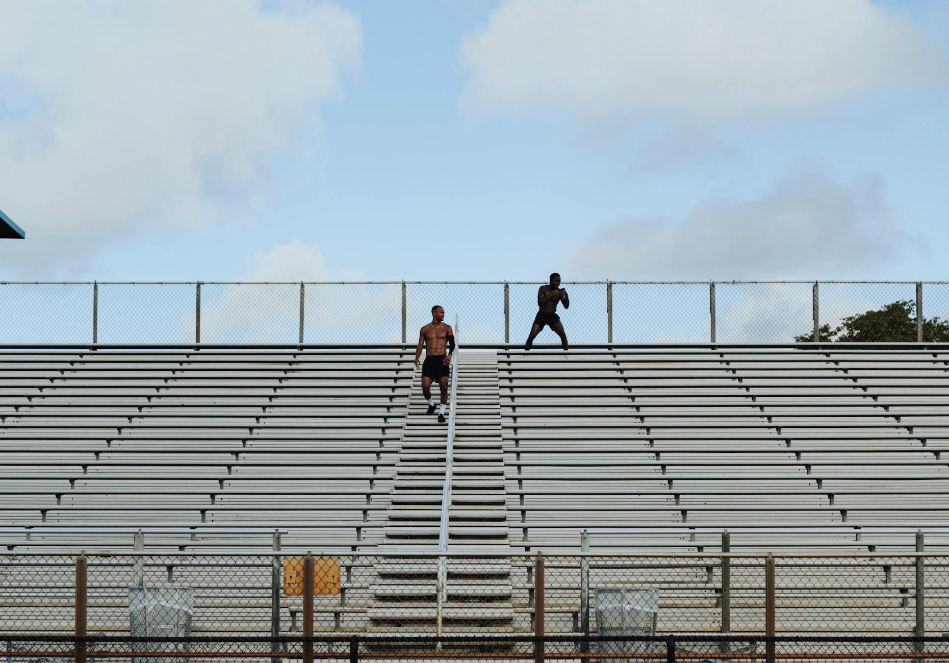 Two men exercising on stadium bleachers highlighting endurance and fitness outdoors. - high intensity cardio