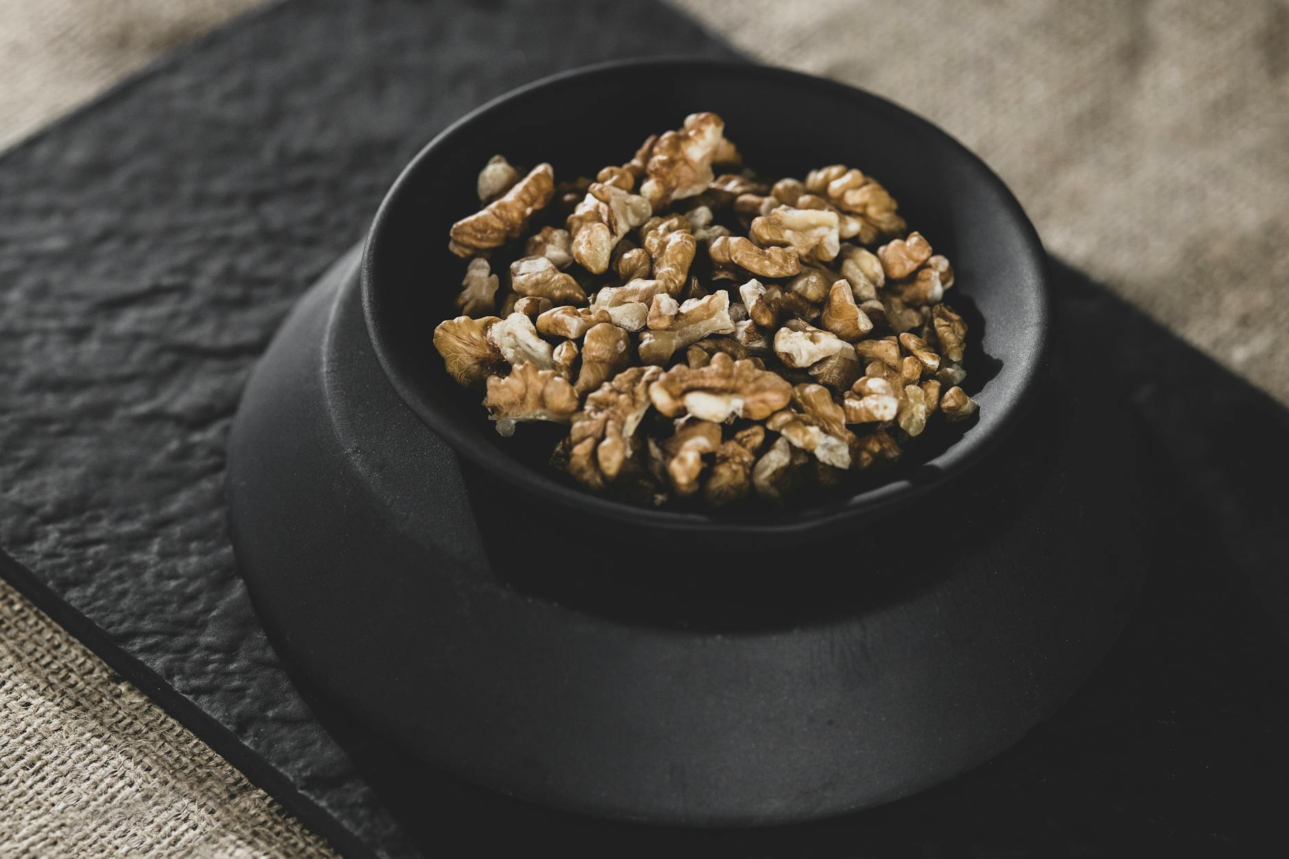 Nutritious organic walnuts in a black bowl, perfect for healthy snacks or raw diets. - high protein snacks