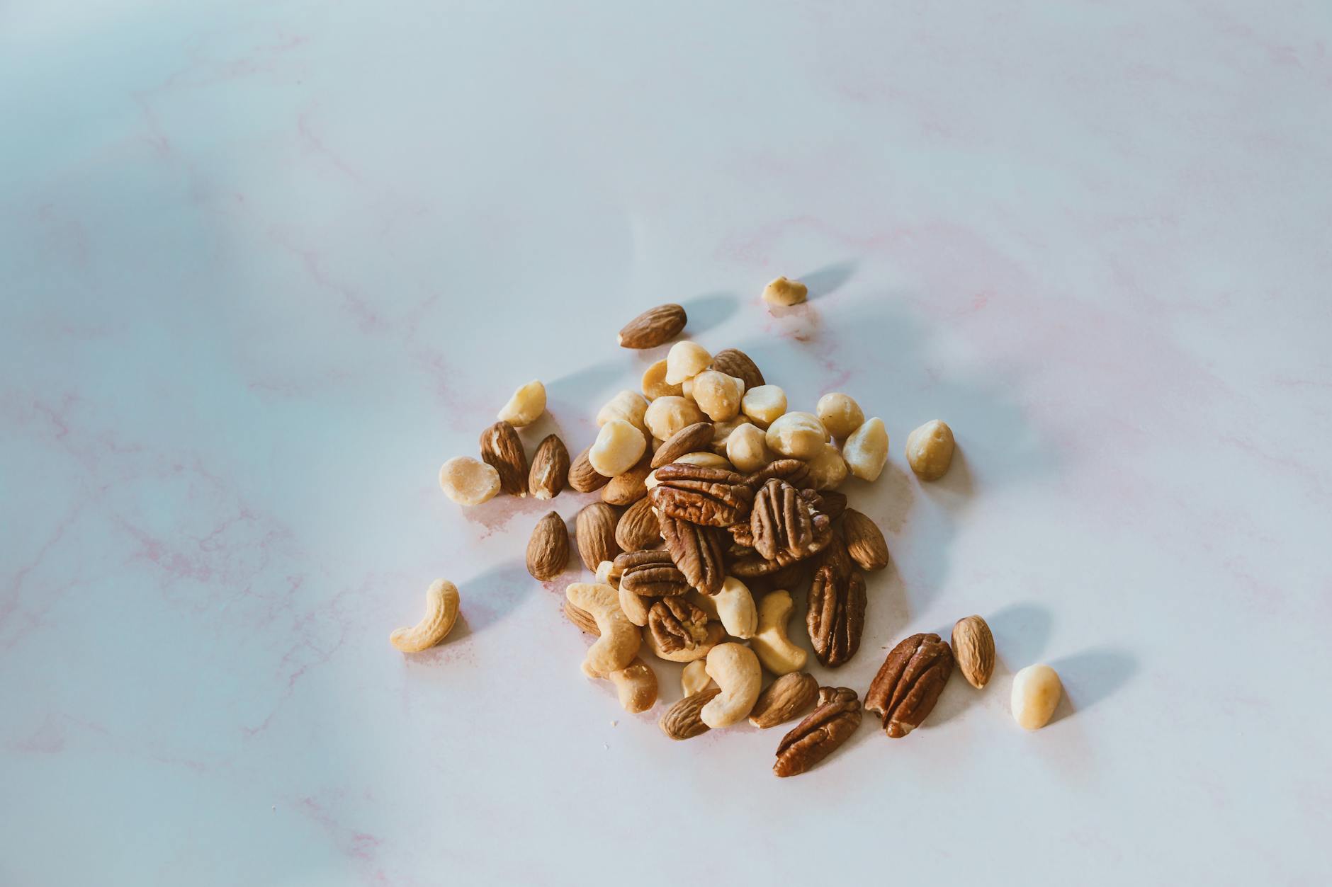 Close-up of assorted nuts on a marble surface, with natural lighting and texture. - high protein snacks
