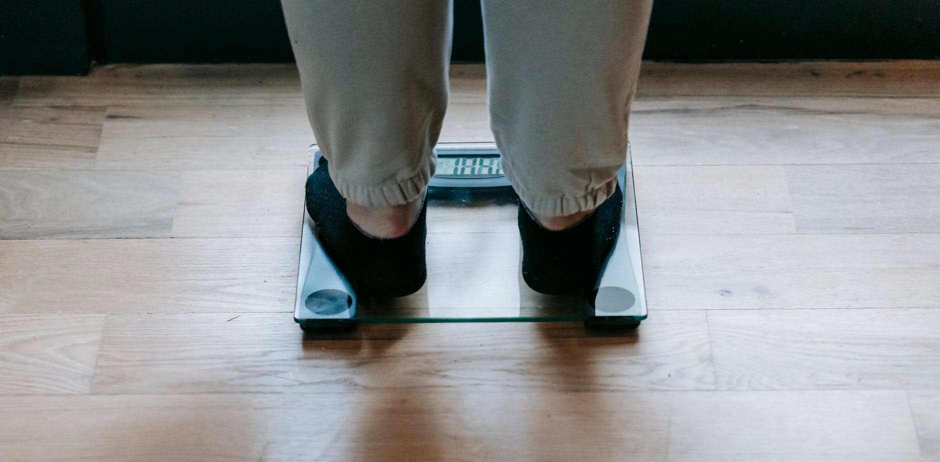 A woman weighing herself on a glass scale indoors, focusing on weight management. - intermittent fasting weight loss