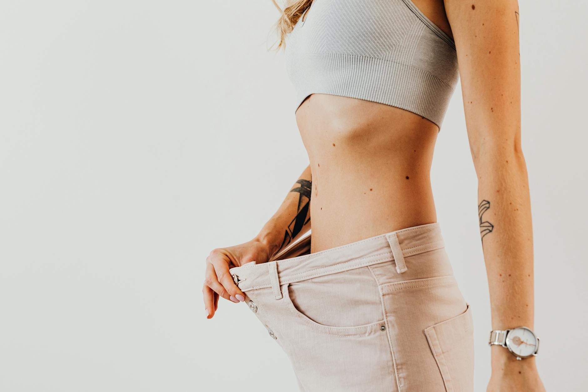 Close-up of a woman in oversized jeans symbolizing weight loss in a studio setting. - intermittent fasting weight loss