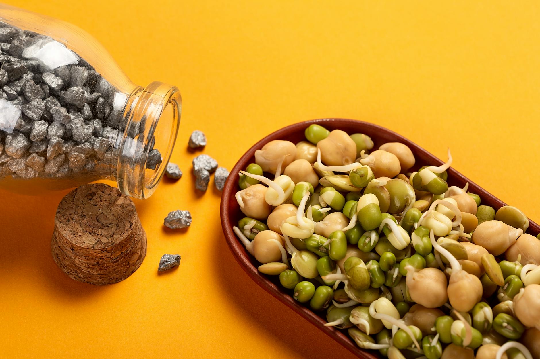 Healthy sprouted chickpeas and beans with iron nuggets on a vibrant yellow backdrop. - iron protein foods