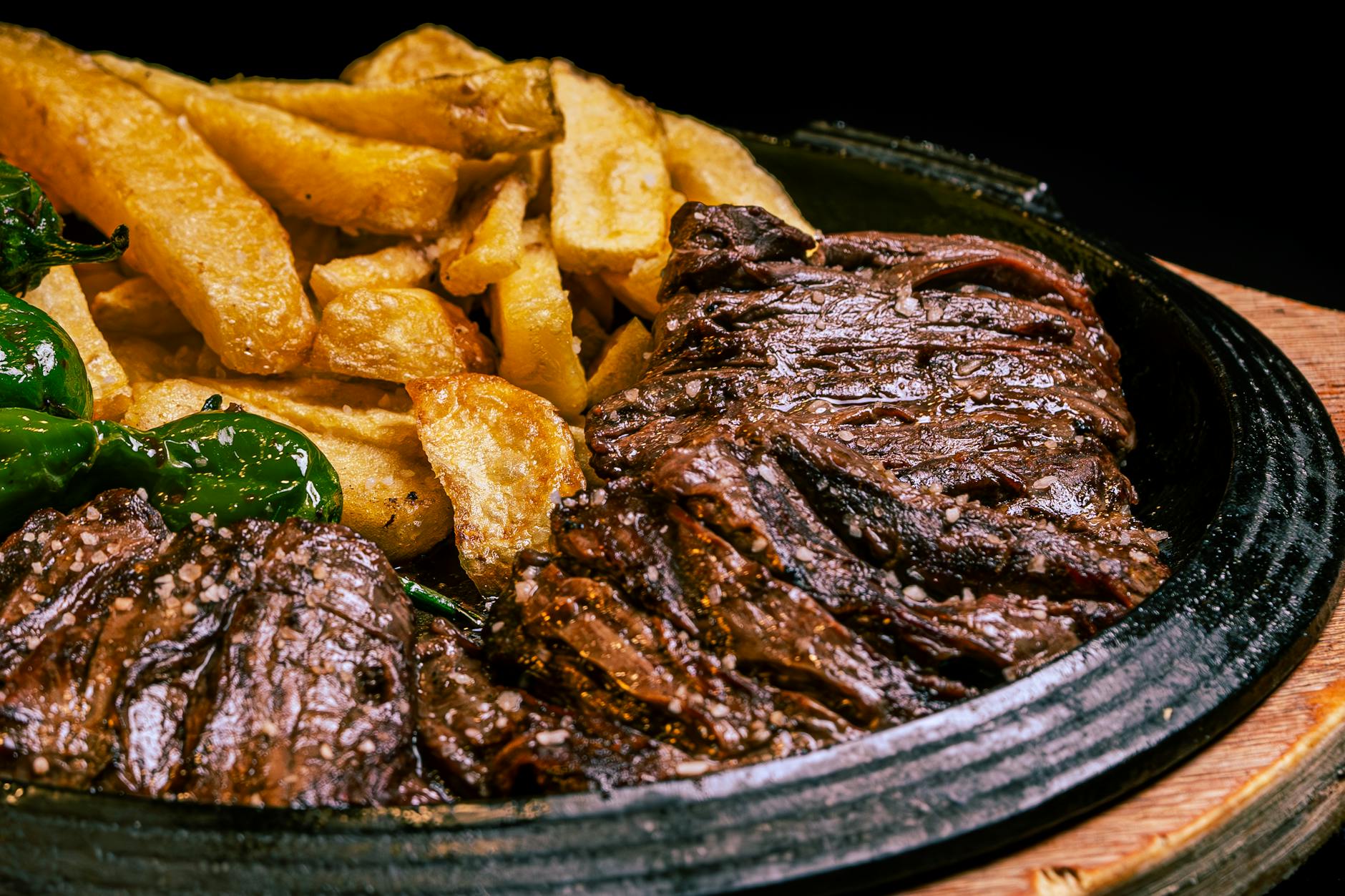 Juicy grilled steak paired with crispy fries and green peppers on a rustic plate. - iron protein foods