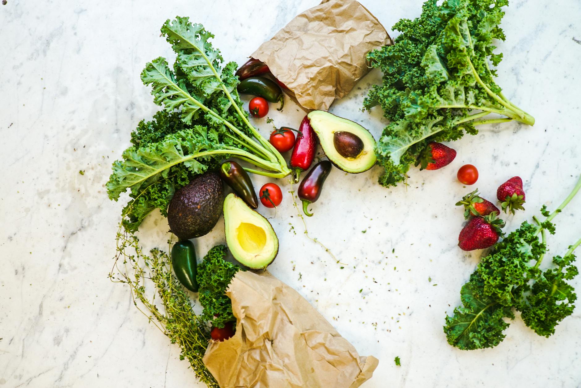 Avocado, kale, and more fresh produce artfully arranged on a marble surface. - keto meal plan