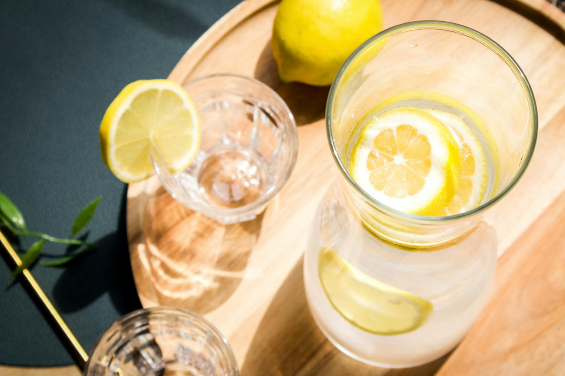 Top view of lemon infused water and glass on a wooden tray, ideal for healthy lifestyle themes. - lemon water benefits