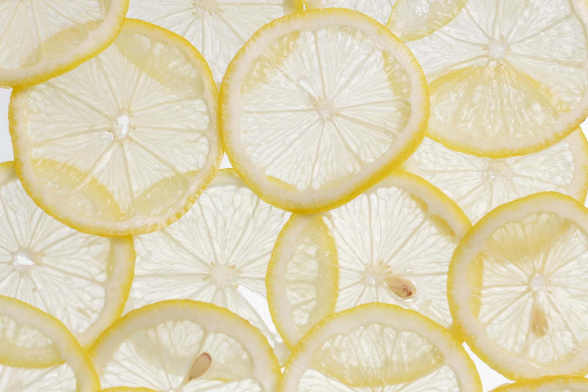 Vibrant close-up of fresh lemon slices arranged on a white surface, showcasing their texture and freshness. - lemon water benefits