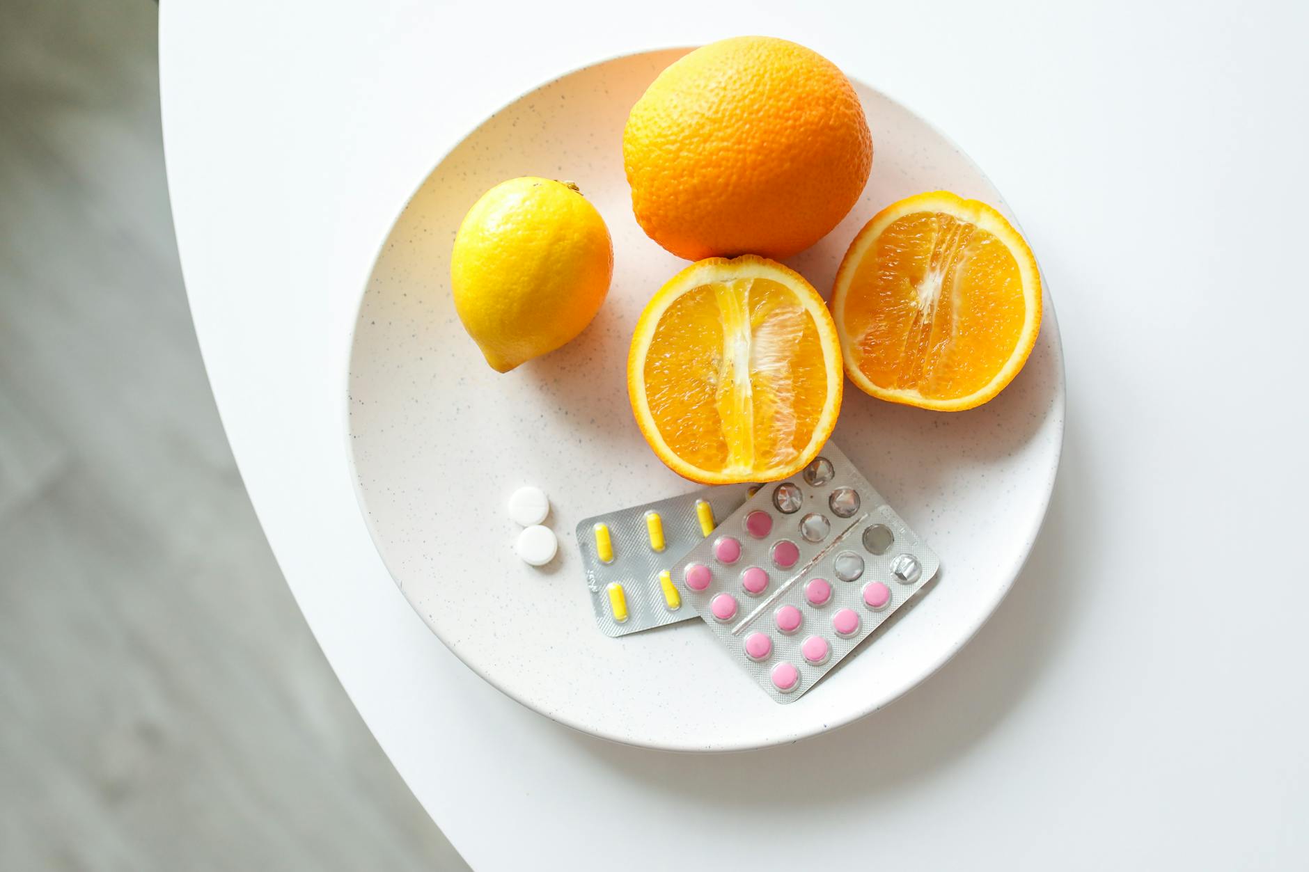 A plate of fresh citrus fruits and blister packs of pills, highlighting nutrition and healthcare. - lemon water benefits