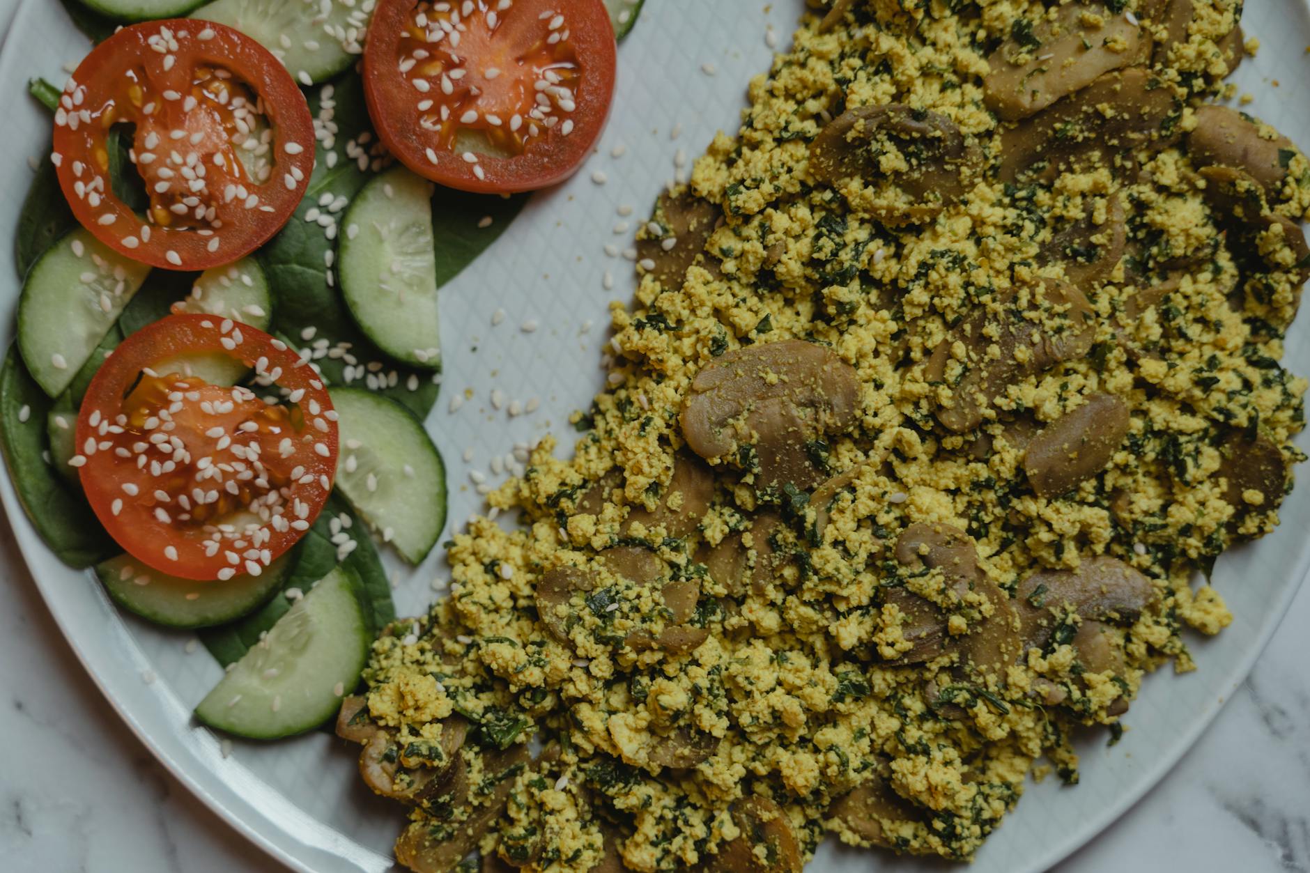 Healthy vegan meal with tofu scramble, cucumbers, and tomatoes on a marble surface. - low carb ground beef recipes