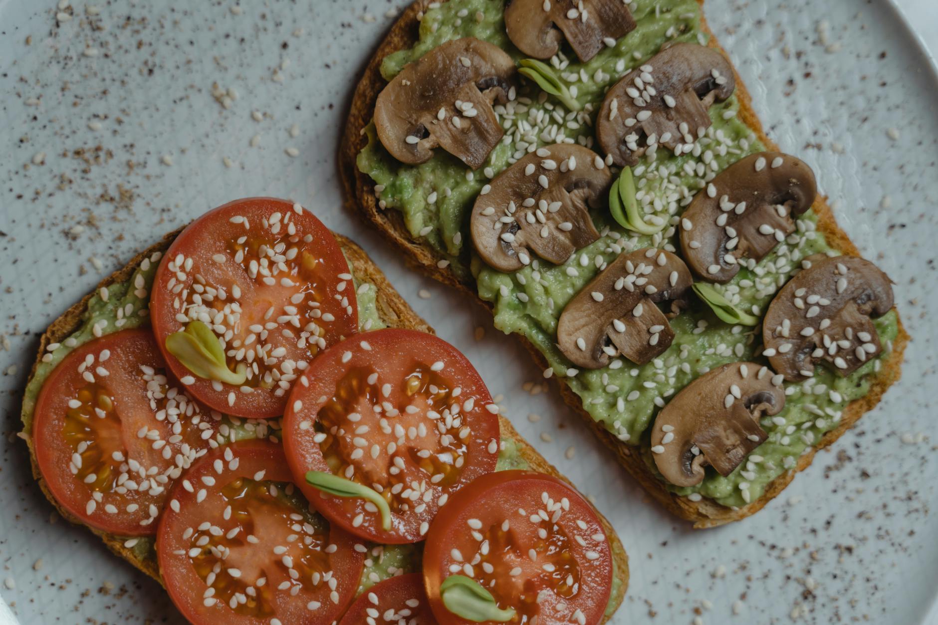 Close-up of vegan avocado toast with fresh tomatoes and mushrooms on a plate. - low carb ground beef recipes