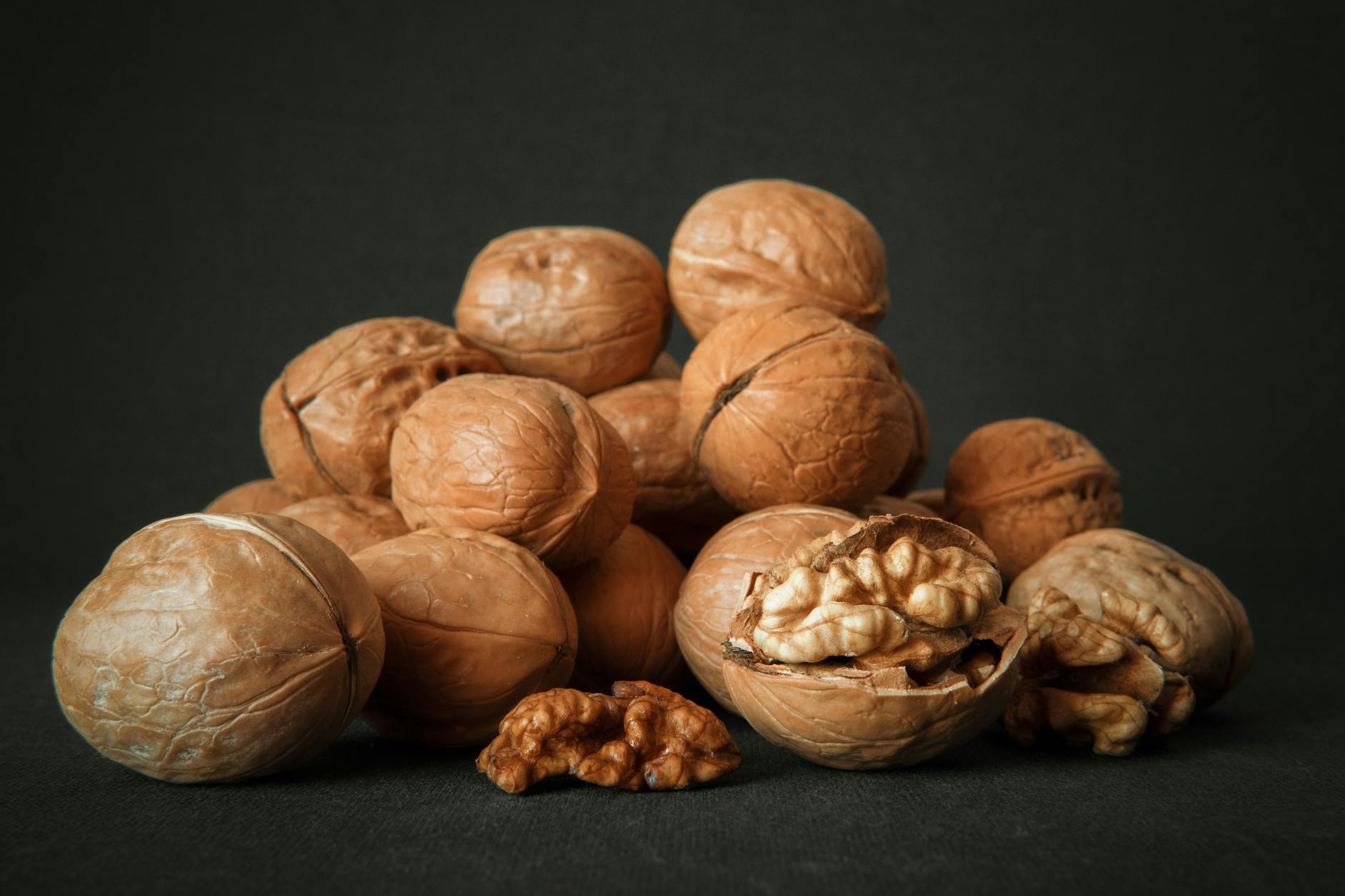 Close-up of whole and cracked walnuts on a dark background highlighting texture and detail. - magnesium citrate benefits