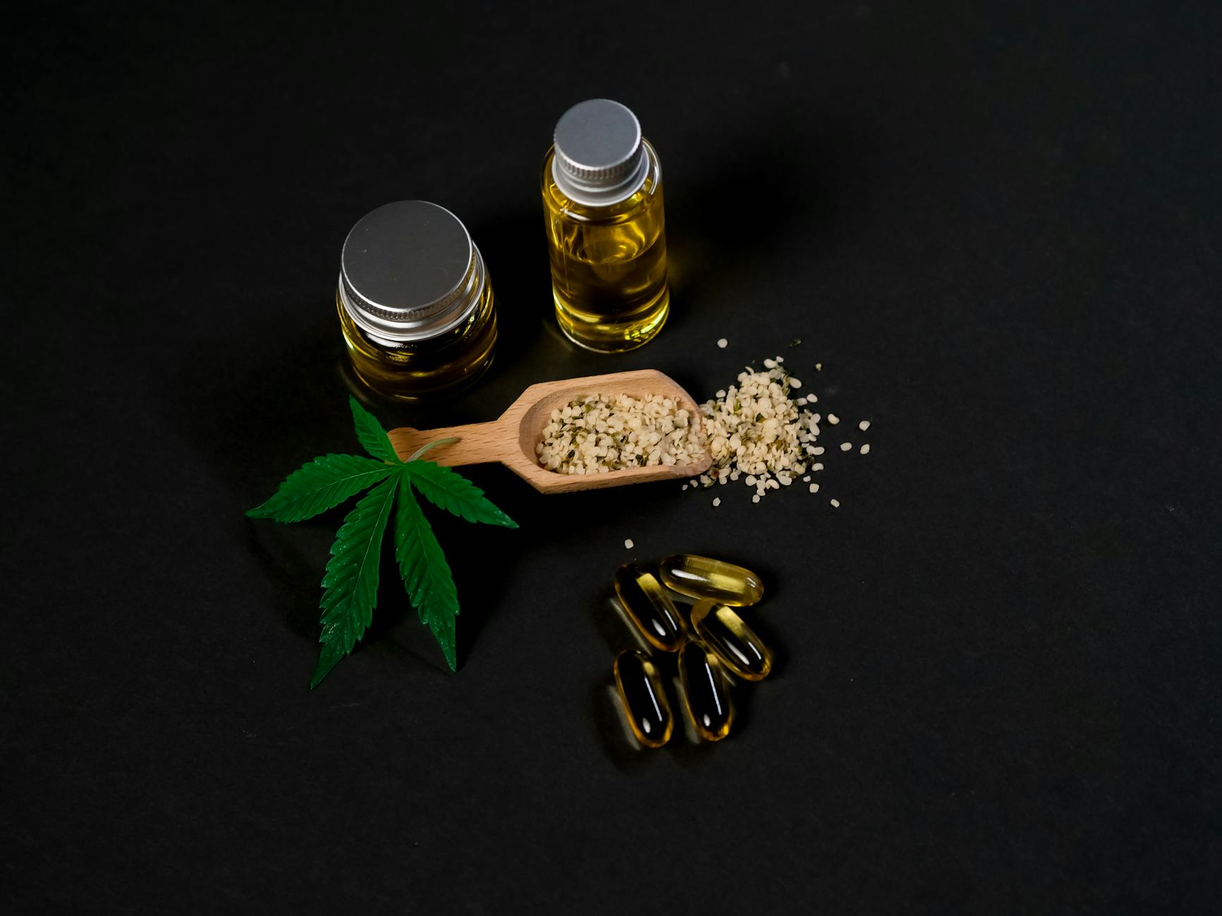 High-quality cannabis oil and capsules with hemp seeds and leaf on a dark backdrop. - magnesium oil benefits