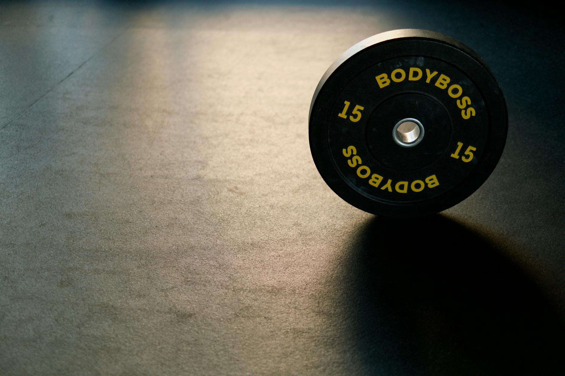 Black BodyBoss weight plate on gym floor, ideal for fitness and workout themes. - maintain weight travel