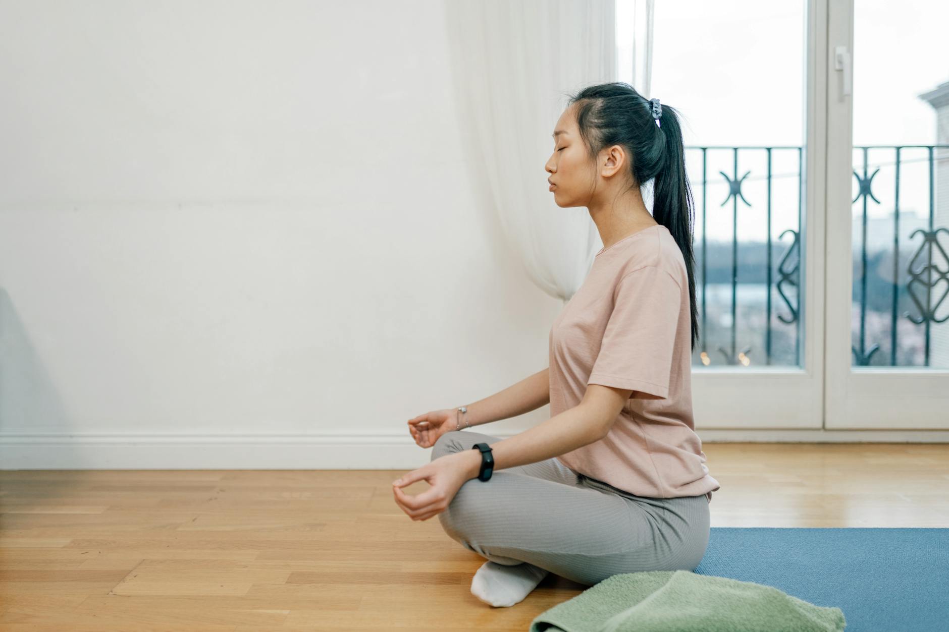 Asian woman meditating indoors on a yoga mat, exuding calm and serenity. - mental wellness practices