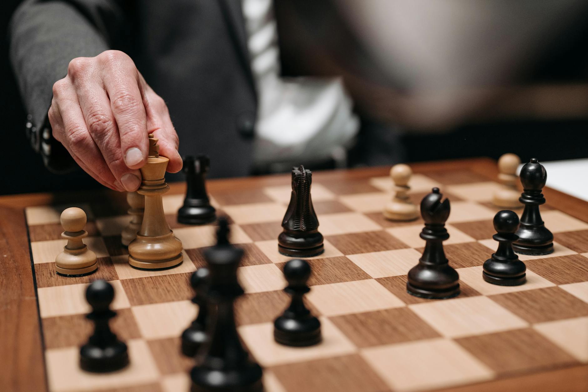 Close-up of a hand making a strategic chess move on a wooden chessboard. - mindful movement