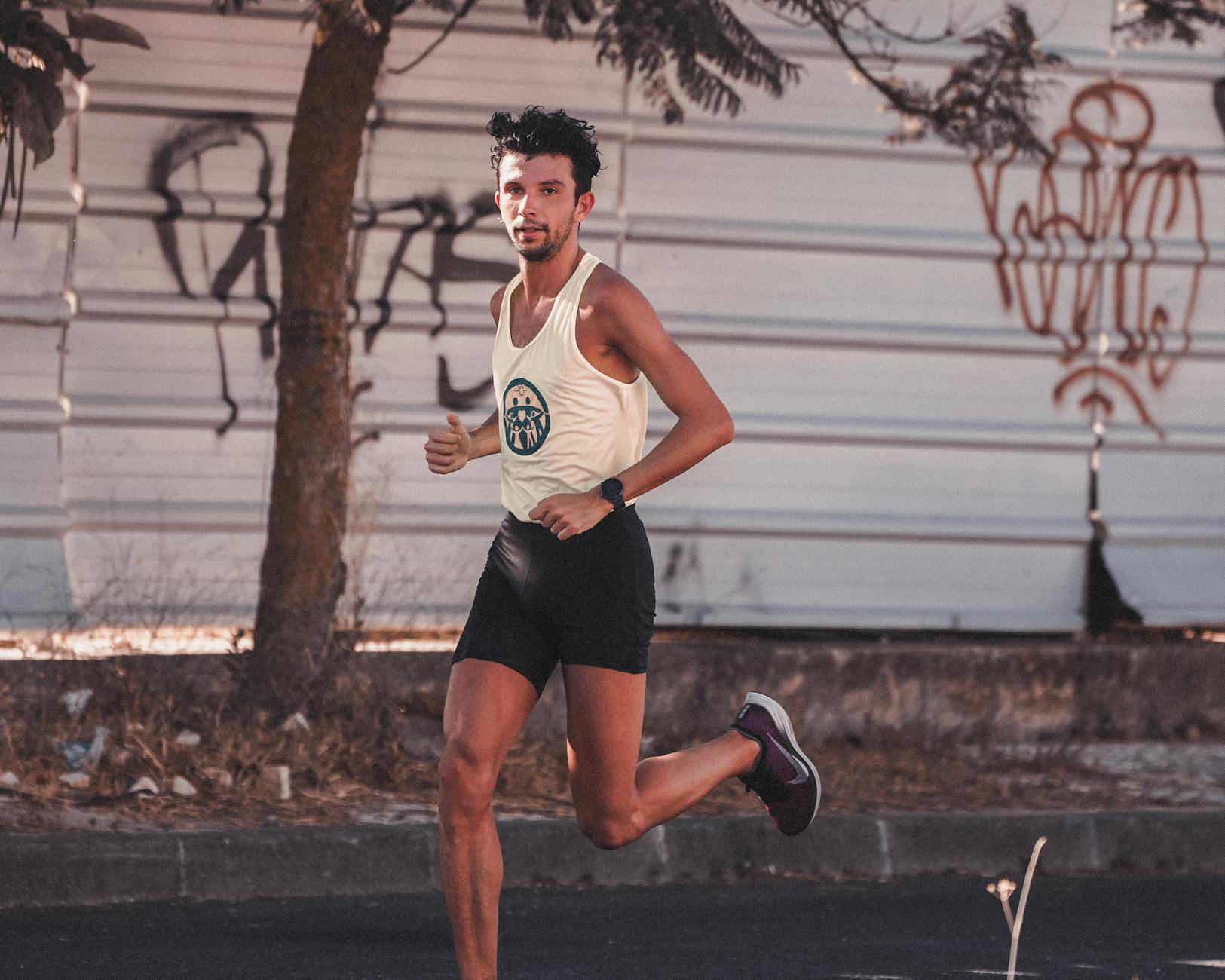 Athletic young man jogging outdoors by graffiti wall, exuding energy and fitness. - morning muscle activation