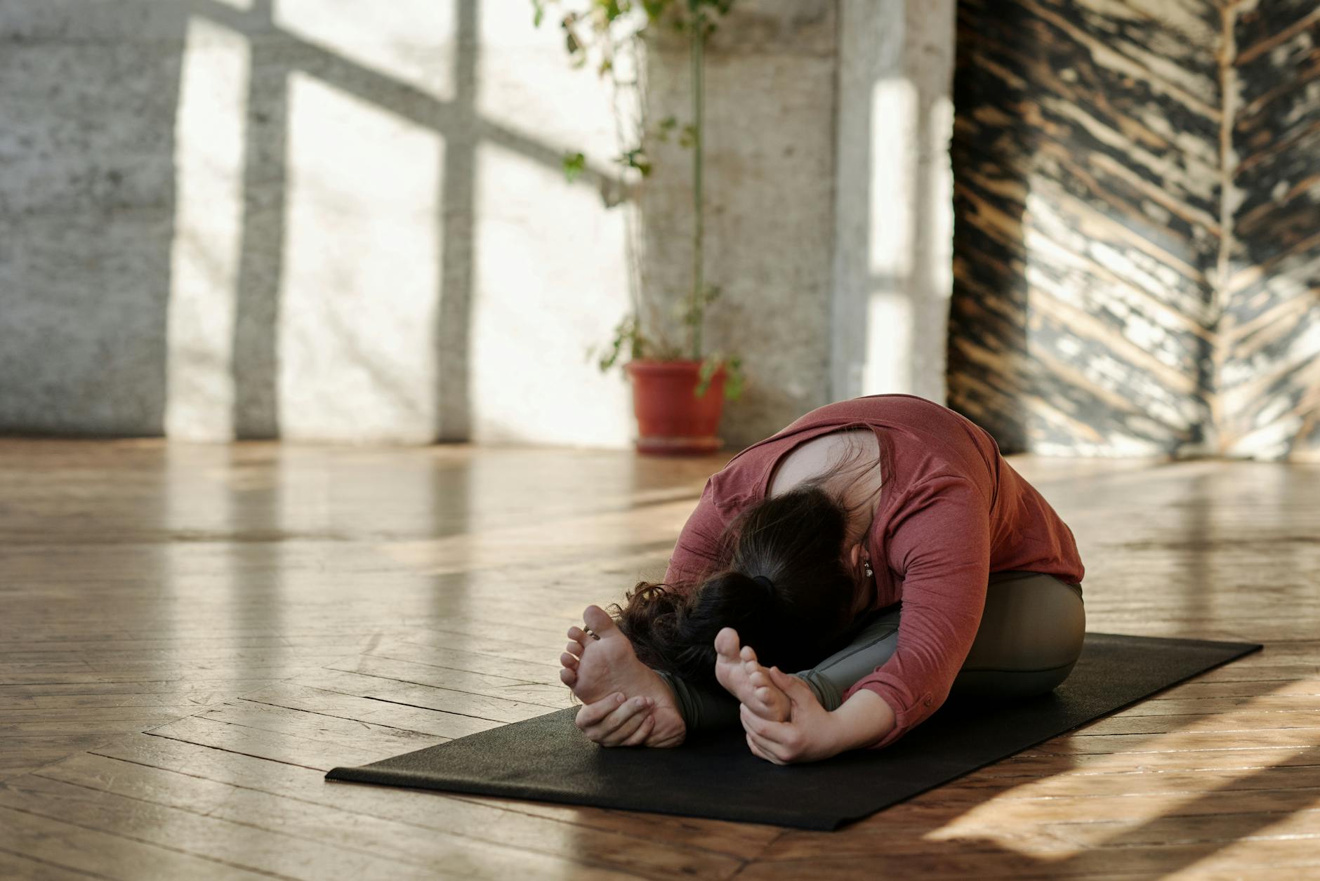A woman stretches on a yoga mat in a sunlit room, embracing relaxation and wellness. - morning stretch routine
