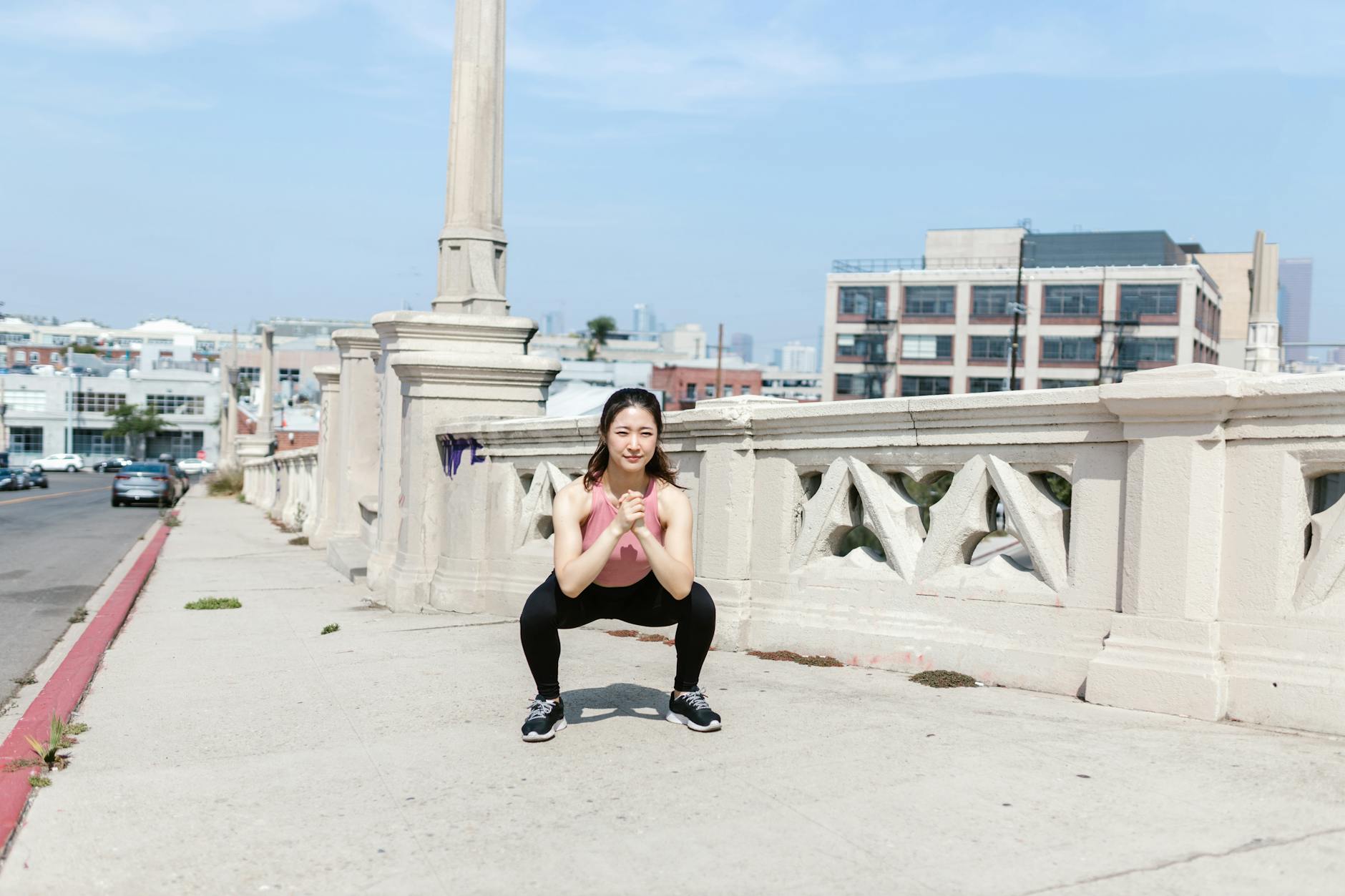 Woman exercising outdoors, performing squats on a city sidewalk. - morning stretch routine