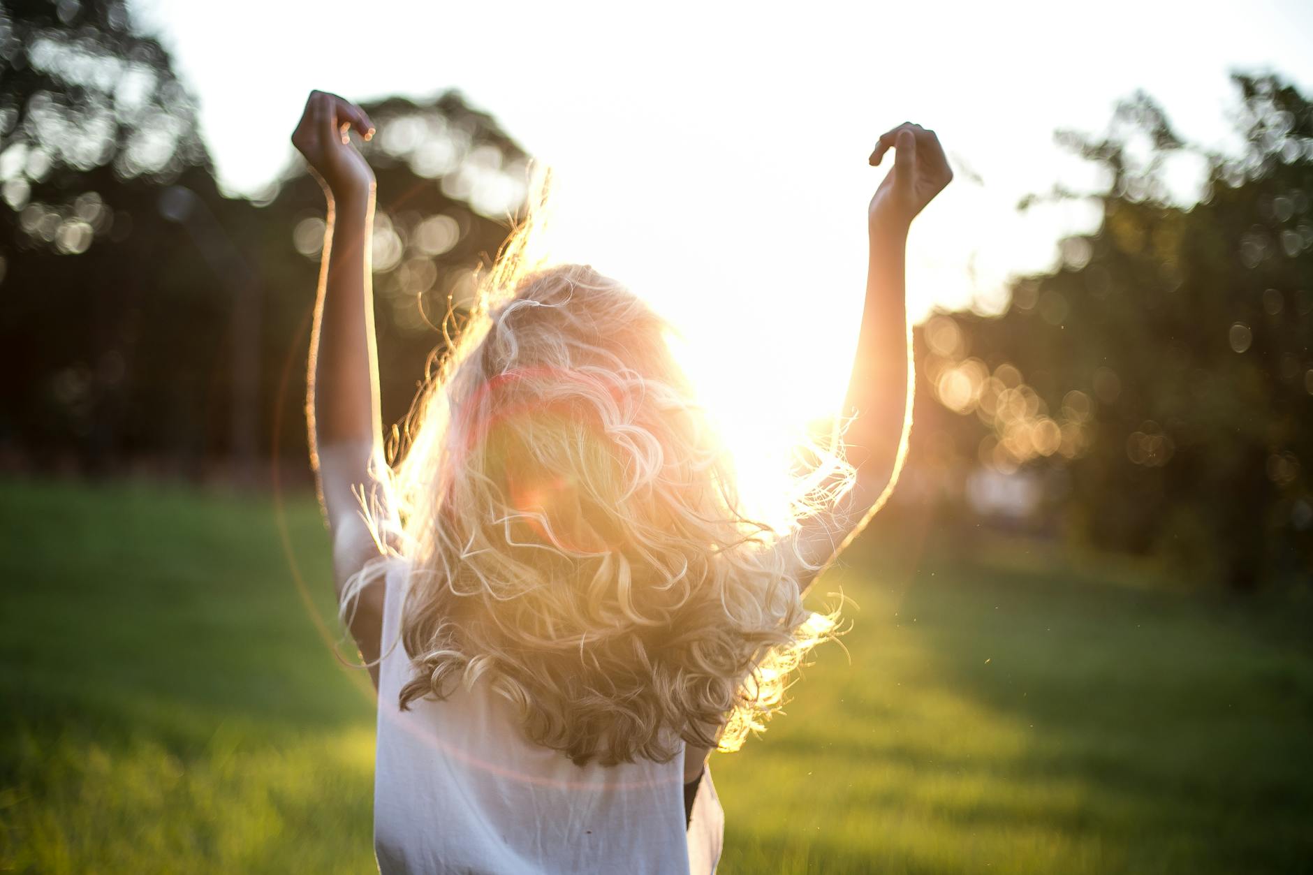 A woman with outstretched arms celebrates the sunset in a grassy field, capturing the essence of freedom and joy. - natural energy boost