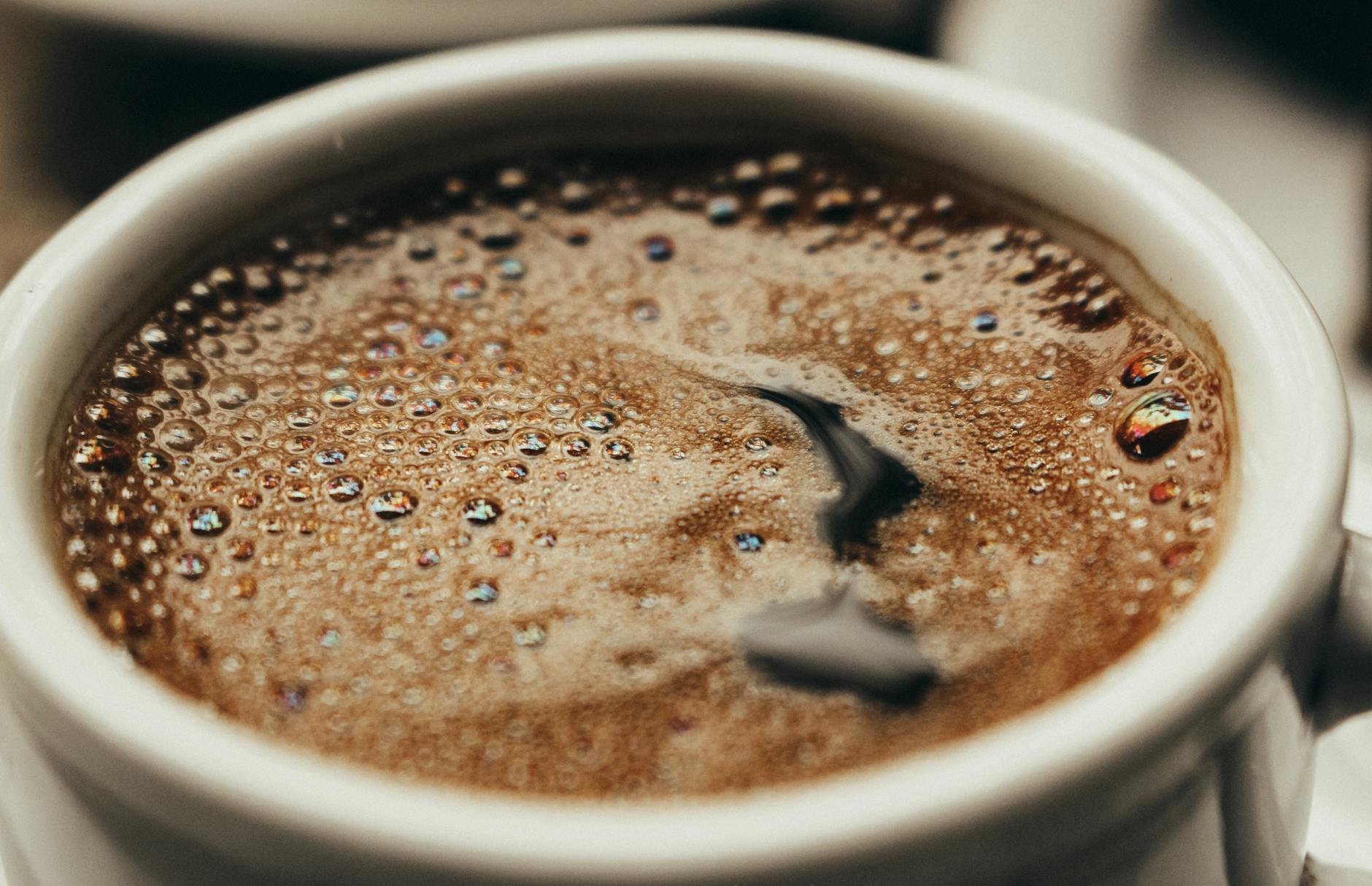 A close-up photo showcasing freshly brewed coffee in a white cup with visible bubbles. - natural energy boost