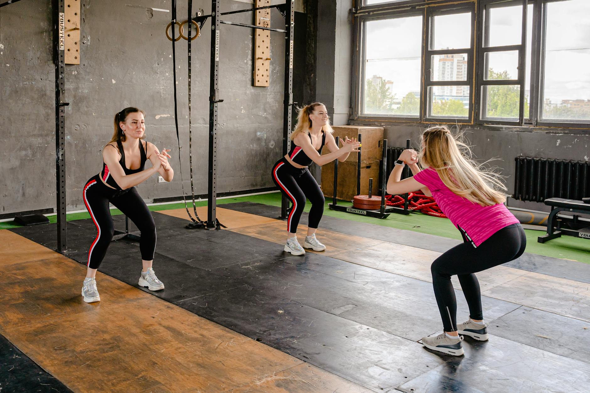 A group of women exercising inside a gym, performing squats in sportswear. - neck posture exercises