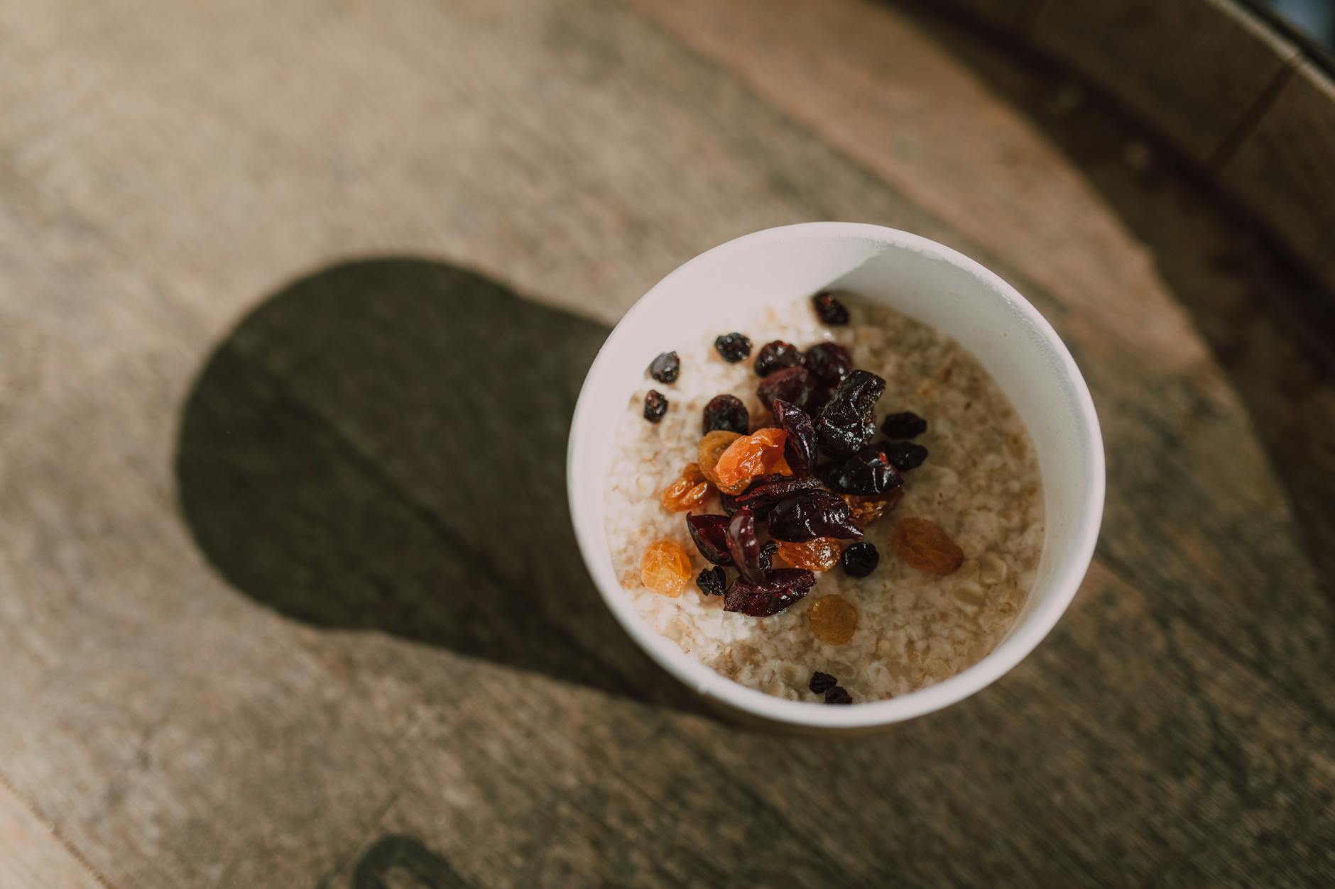 A nutritious bowl of oatmeal topped with a variety of dried fruits photographed from above. - oatmeal benefits