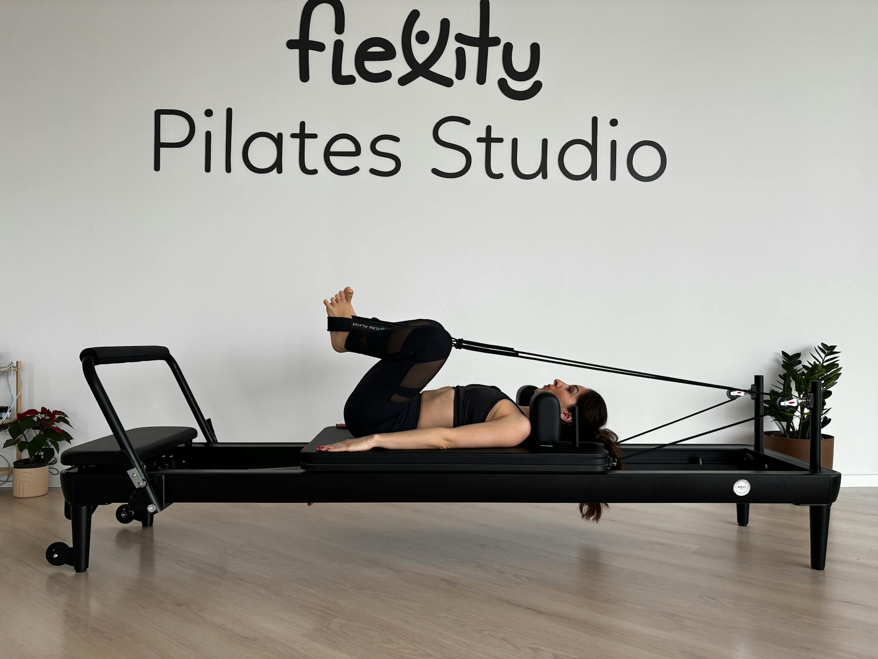 Woman practicing Pilates on a reformer machine in a modern studio setting. - what is pilates
