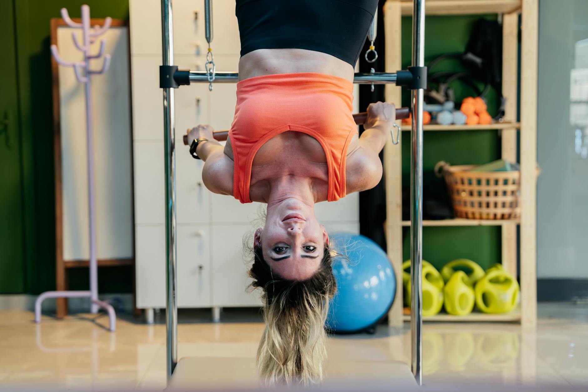 Woman practicing inverted Pilates on a reformer at a gym, focused on fitness and flexibility. - pilates chair exercises