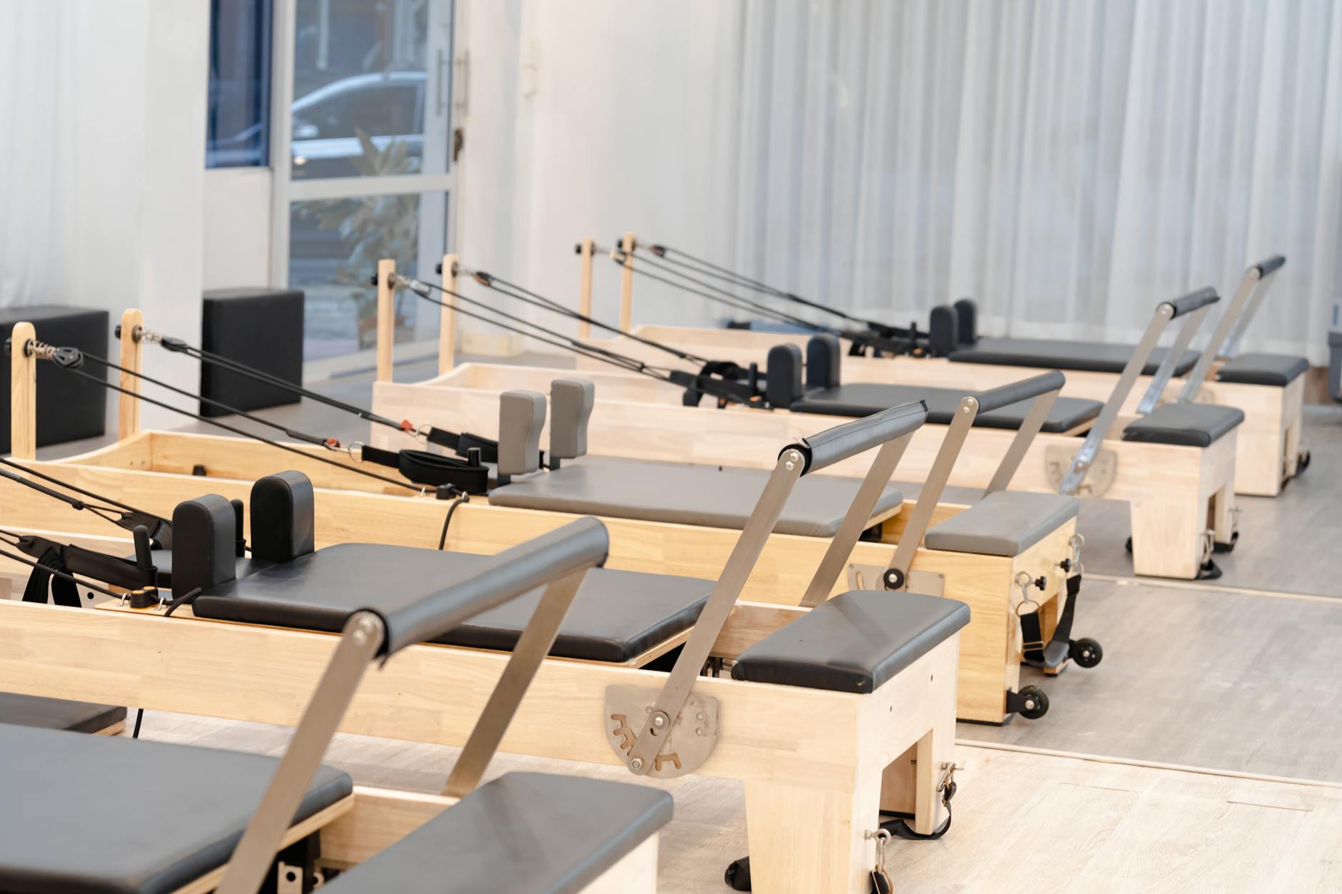 A contemporary Pilates studio equipped with multiple wooden reformers for fitness training. - pilates reformer exercises