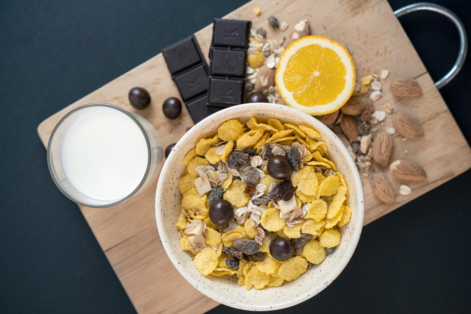 A close-up of a nutritious breakfast featuring cereal, chocolate, orange, and milk on a wooden board. - probiotic foods boost