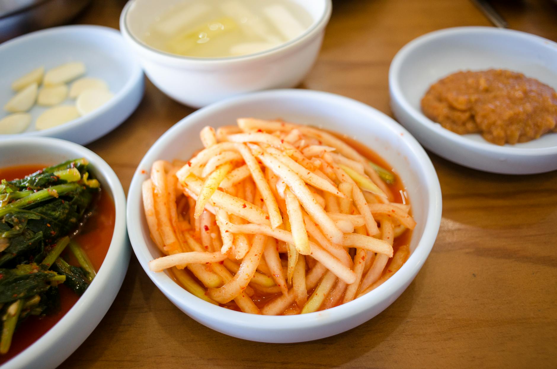 An assortment of Korean side dishes displayed on a wooden table with vibrant colors. - probiotic rich foods