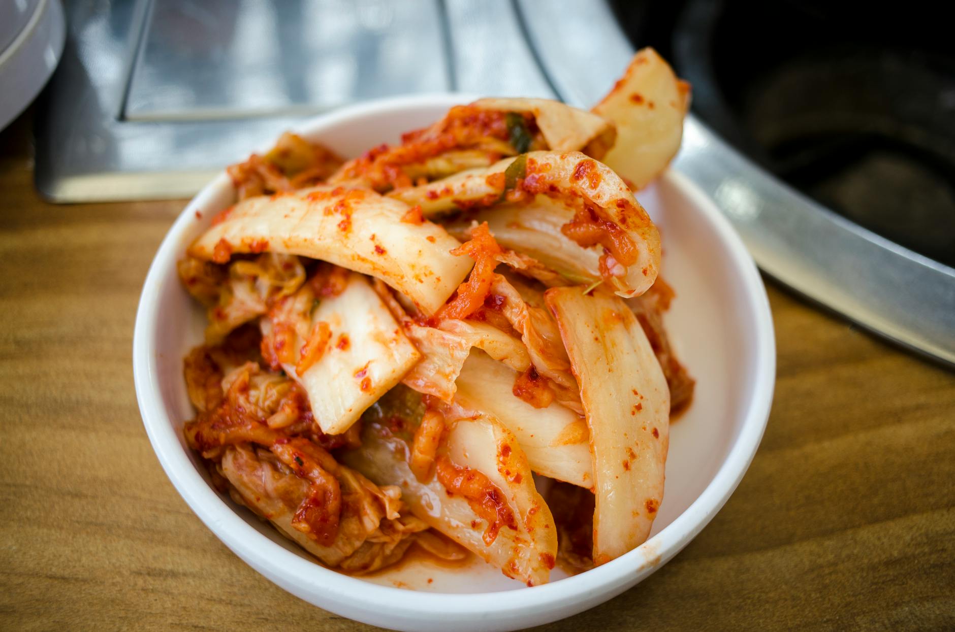 Close-up of spicy Korean kimchi in a white ceramic bowl, perfect for food enthusiasts. - probiotic rich foods