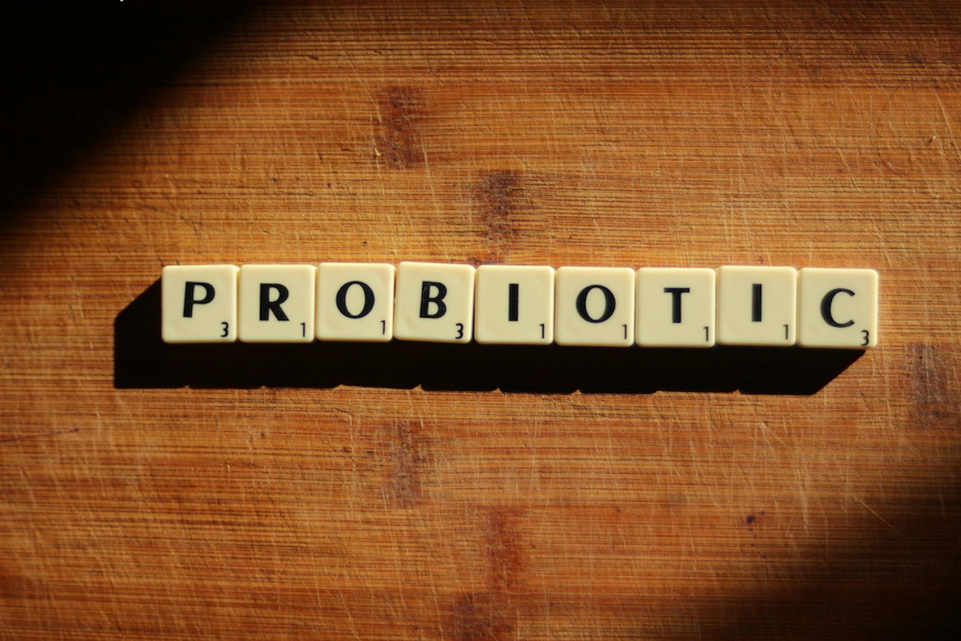 Close-up of the word 'probiotic' crafted from letter tiles on a wooden surface. - probiotics benefits