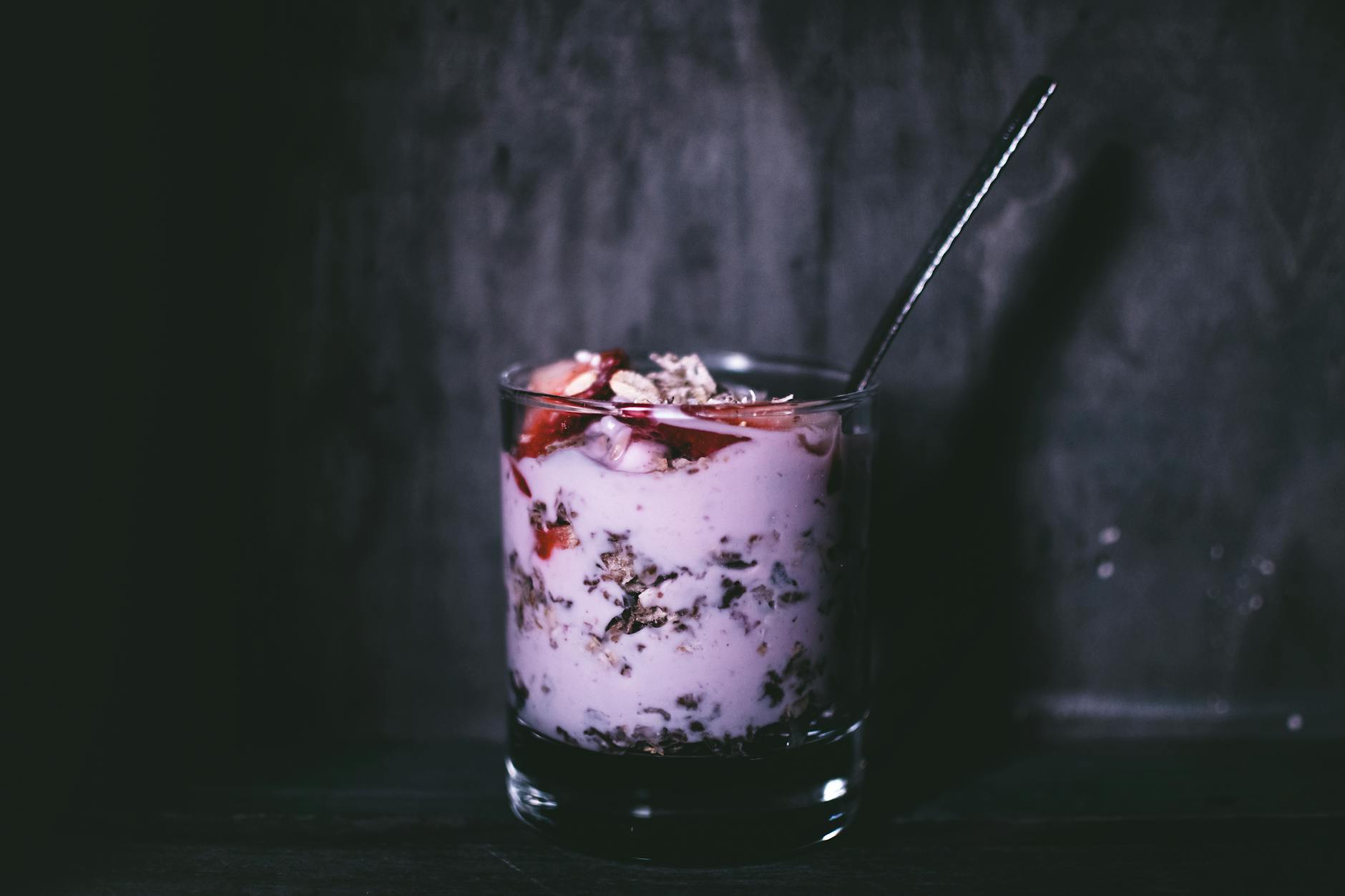 Dark, moody close-up of a delicious yogurt parfait with granola and berries in a glass. - probiotics benefits
