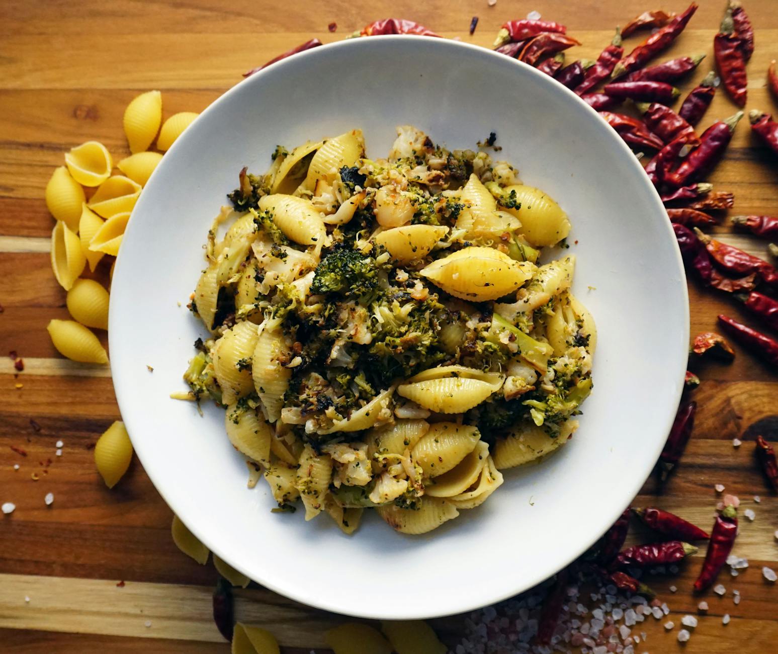 A tempting bowl of shell pasta mixed with broccoli and chili peppers on a rustic wooden table. - quick healthy dinners