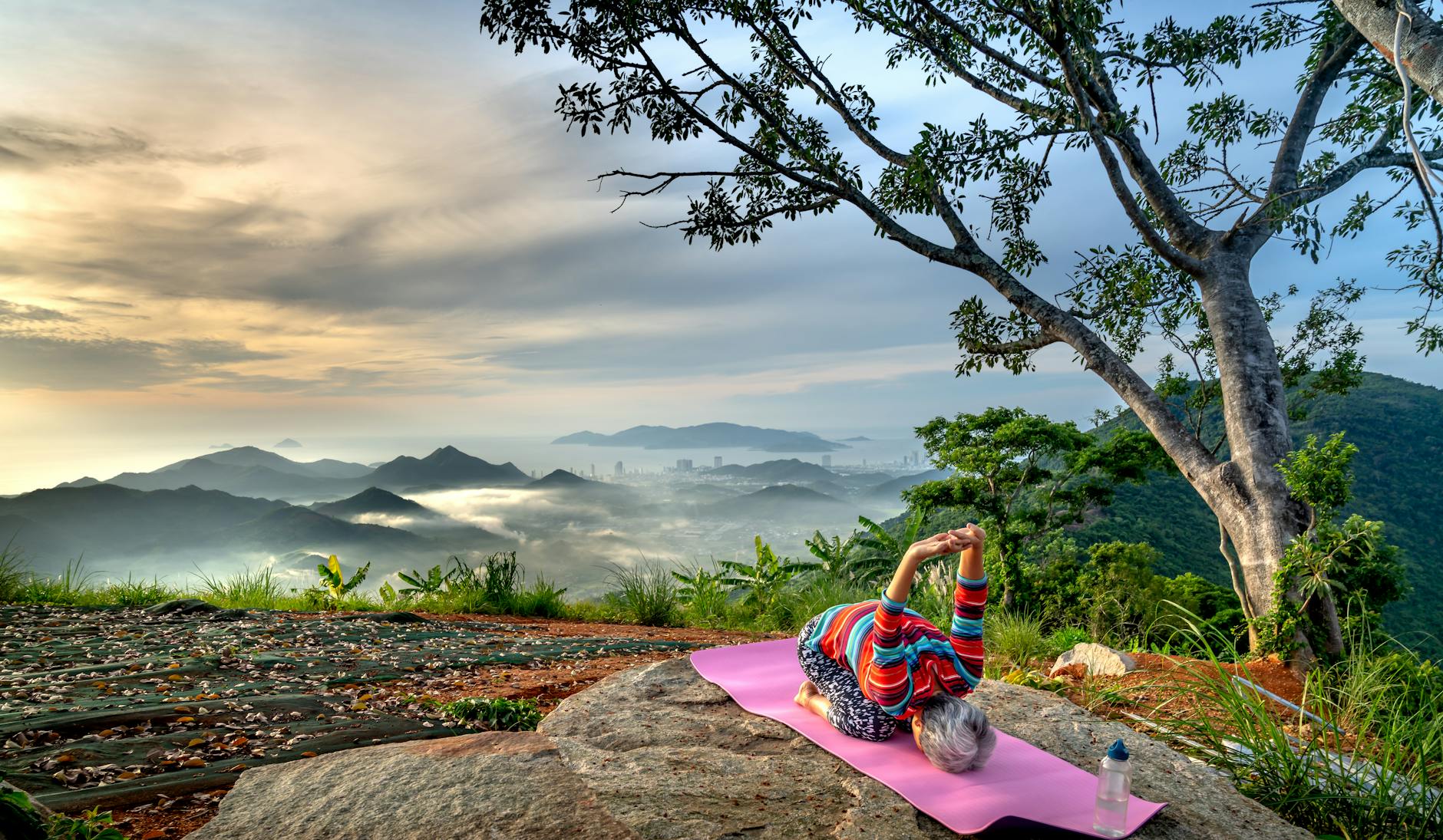 Elderly woman performing yoga on a mountain with a breathtaking view, promoting active and healthy lifestyle. - quick morning yoga