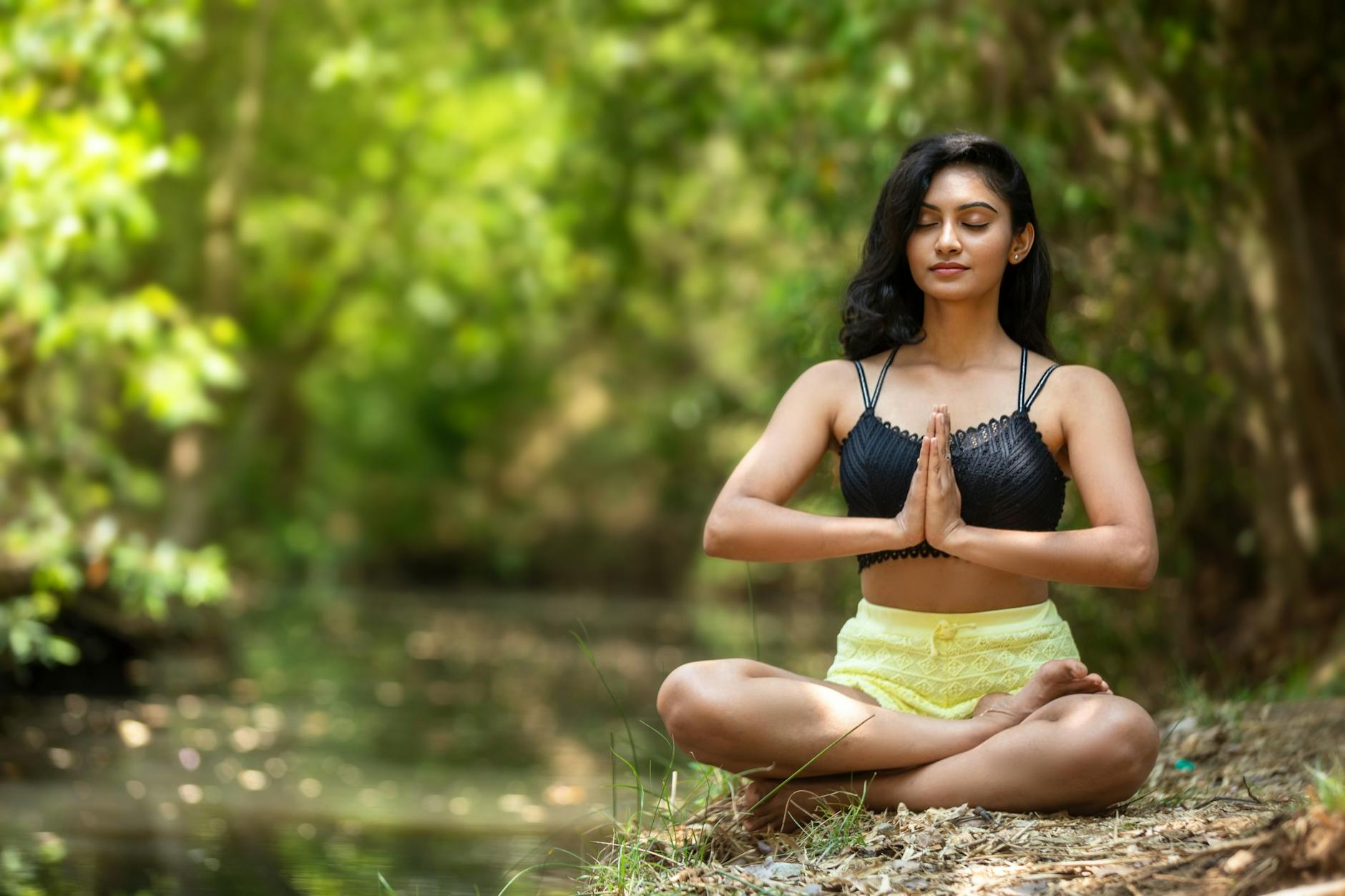 Woman practicing yoga outdoors by a serene water body, embodying peace and mindfulness. - quick morning yoga